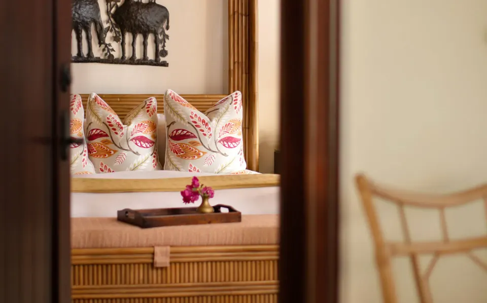 Close-up of bed bench with decorative pillows and a flower tray at Quintessence Hotel