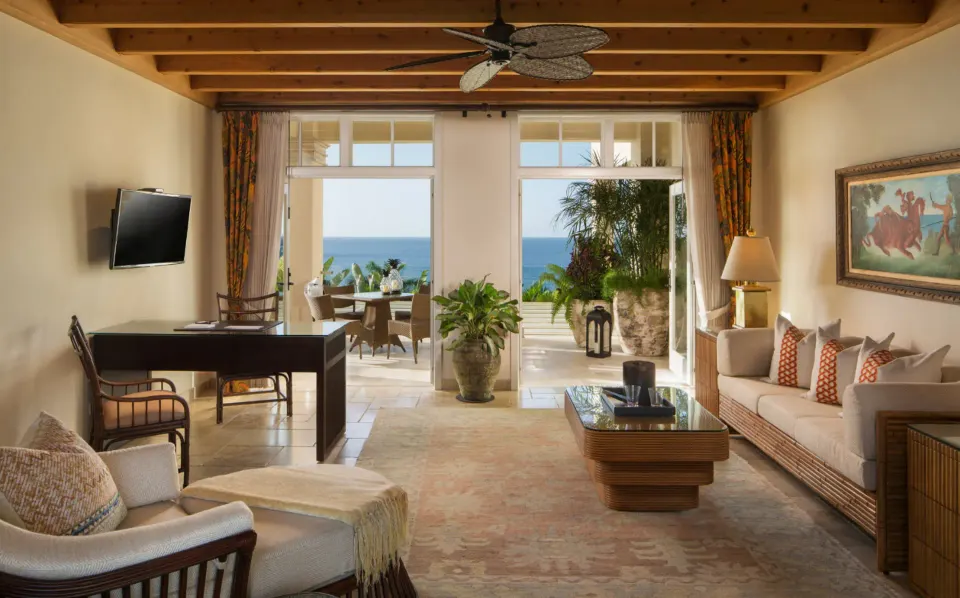 Living area of suite with desk, sofa and open doors to ocean terrace at Quintessence Hotel