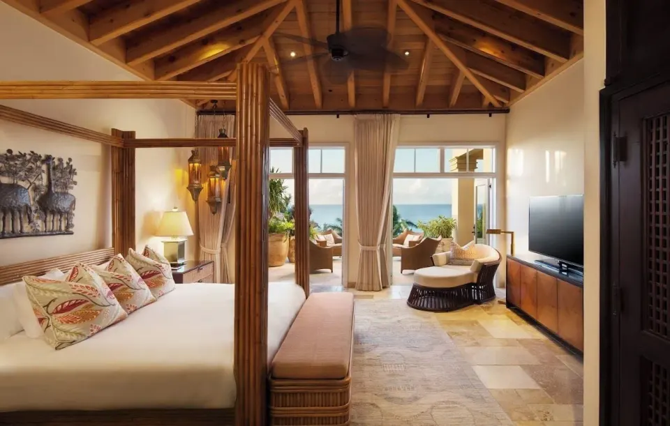 Spacious Premium Room with four-poster king bed and seating area overlooking the ocean at Quintessence Hotel