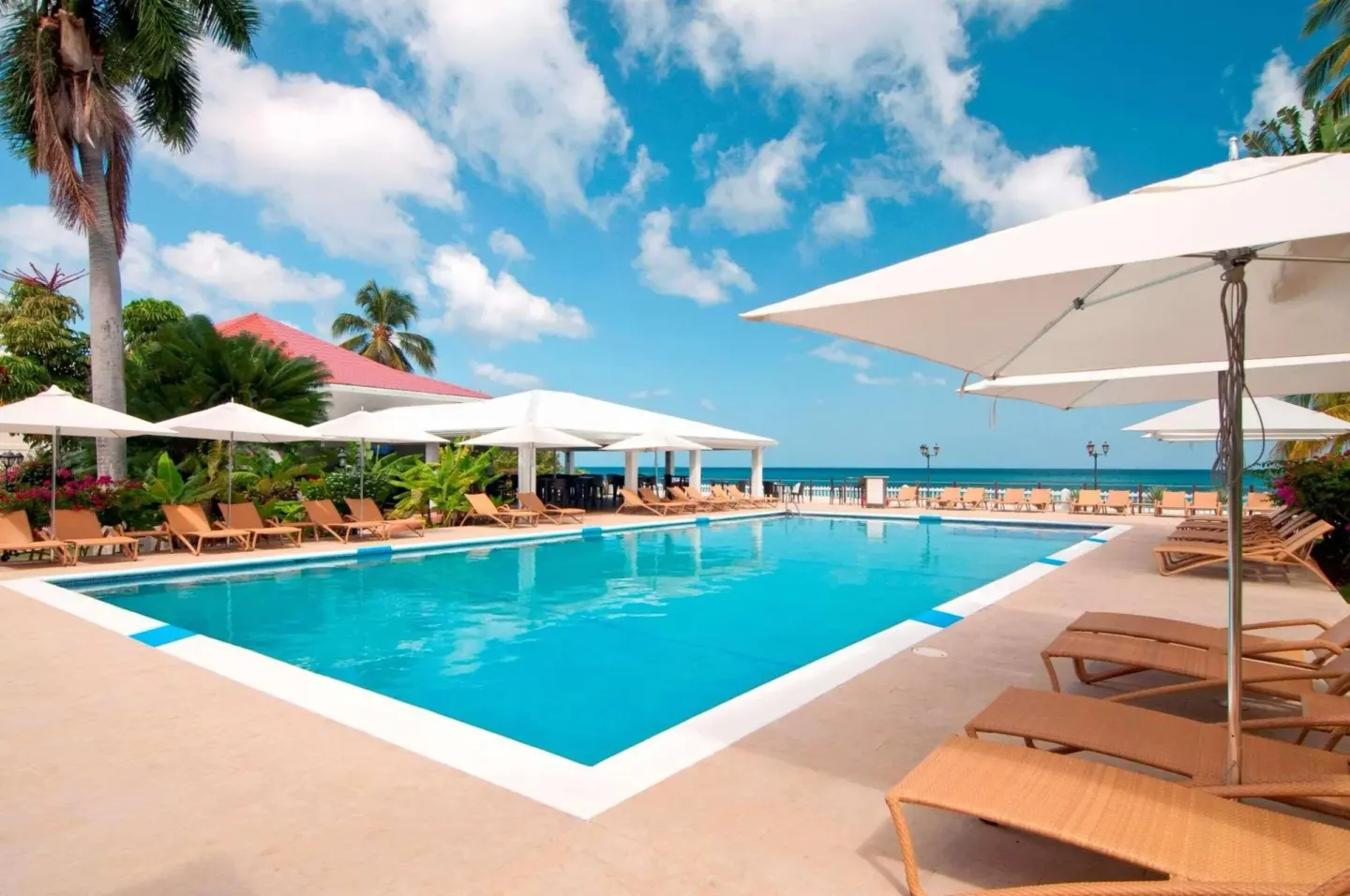 Beachfront pool with umbrellas and lounge chairs at Radisson Grenada Beach Resort.