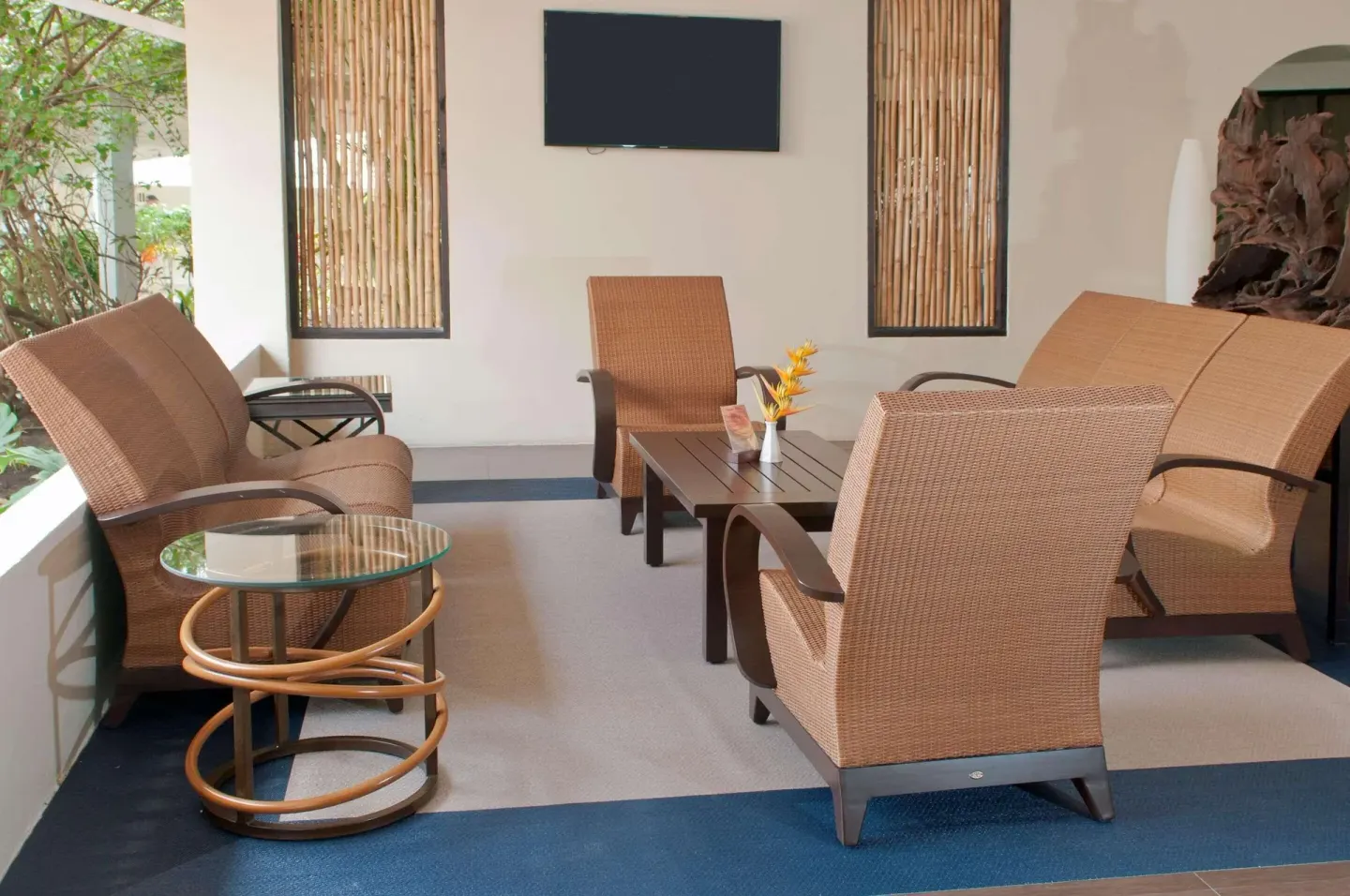 Covered lounge with wicker armchairs and wall-mounted TV at Radisson Grenada Beach Resort.