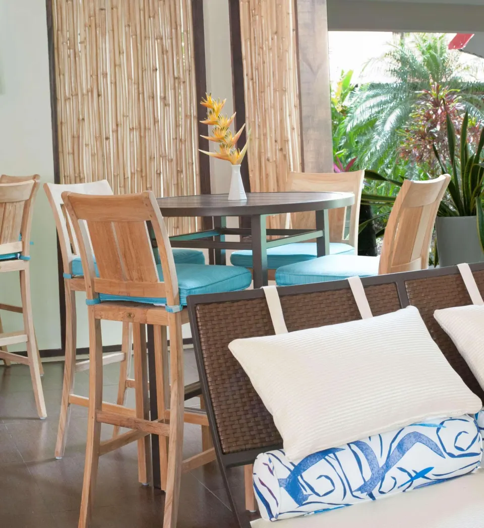 Lounge seating and high table with tropical plants at Radisson Grenada Beach Resort.