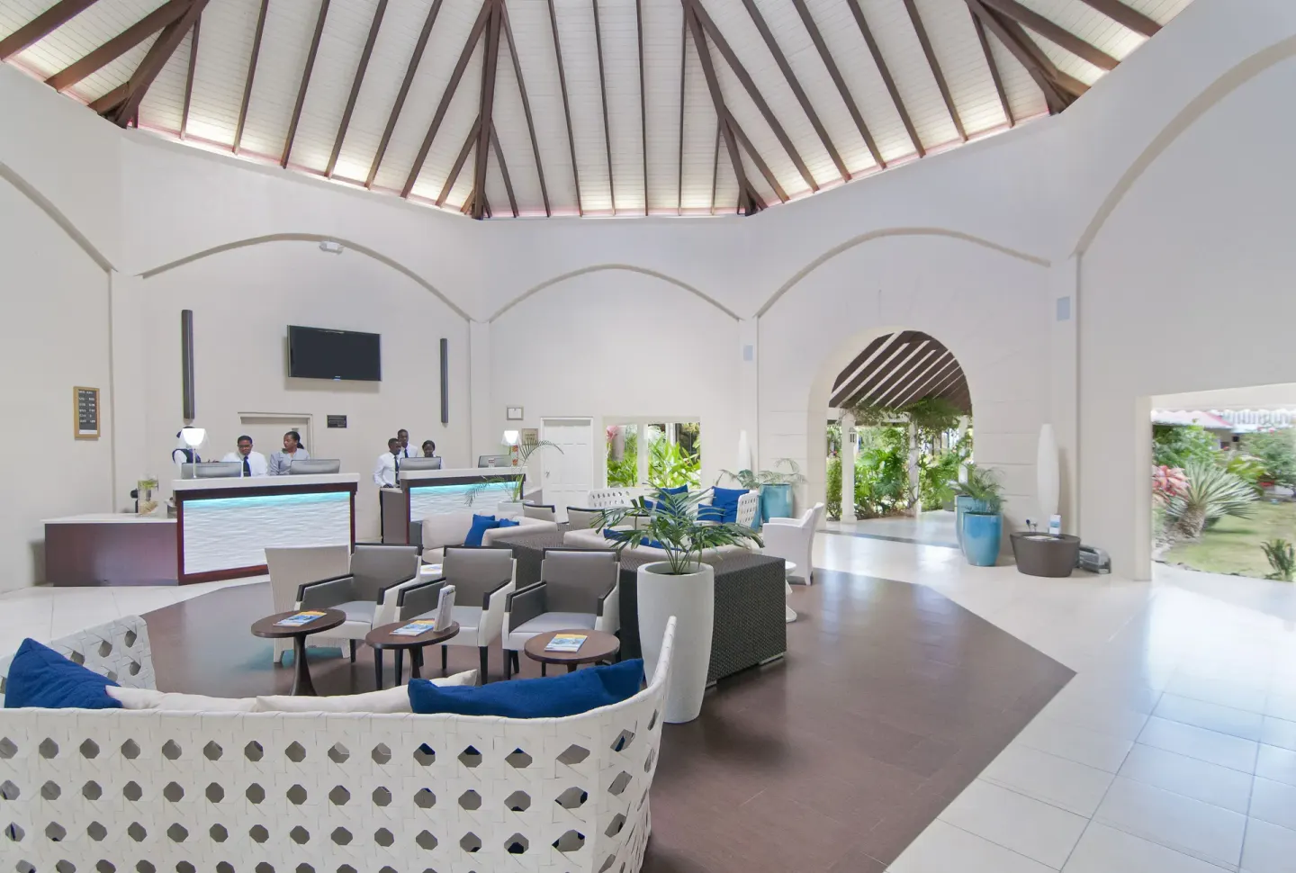 Lobby lounge with reception counters and arched walkways at Radisson Grenada Beach Resort.