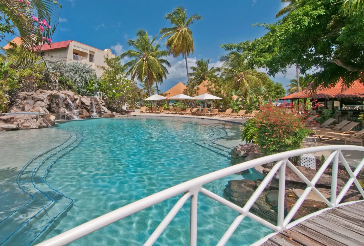 Pool, footbridge, waterfall and red-roofed pavilion at Radisson Grenada Beach Resort.