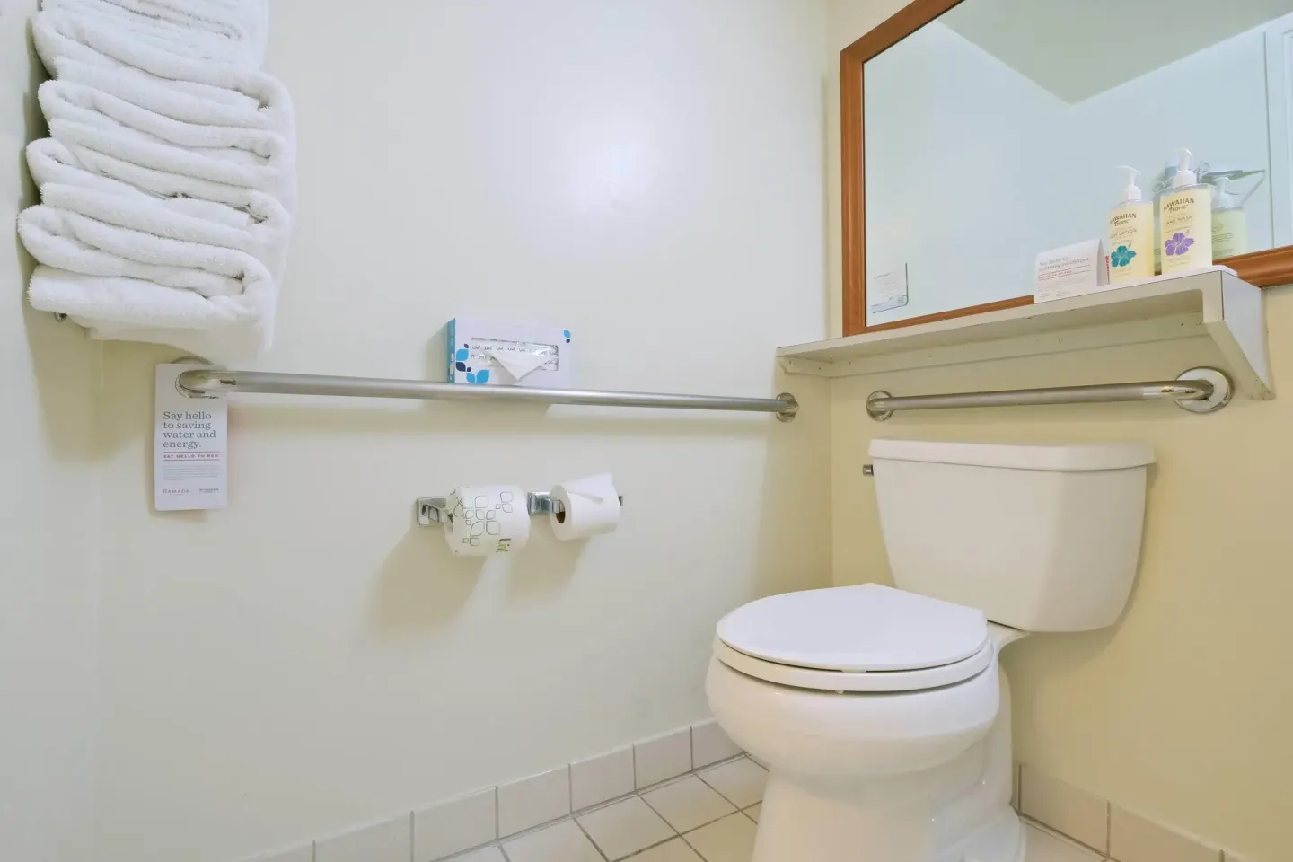Bathroom toilet area with towels and grab bar at Ramada Plaza Waikiki.