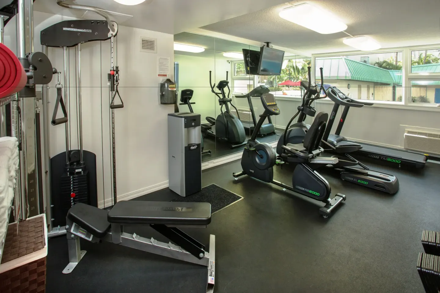 Fitness room with weight machine, bench, treadmill, and bikes at Ramada Plaza Waikiki.