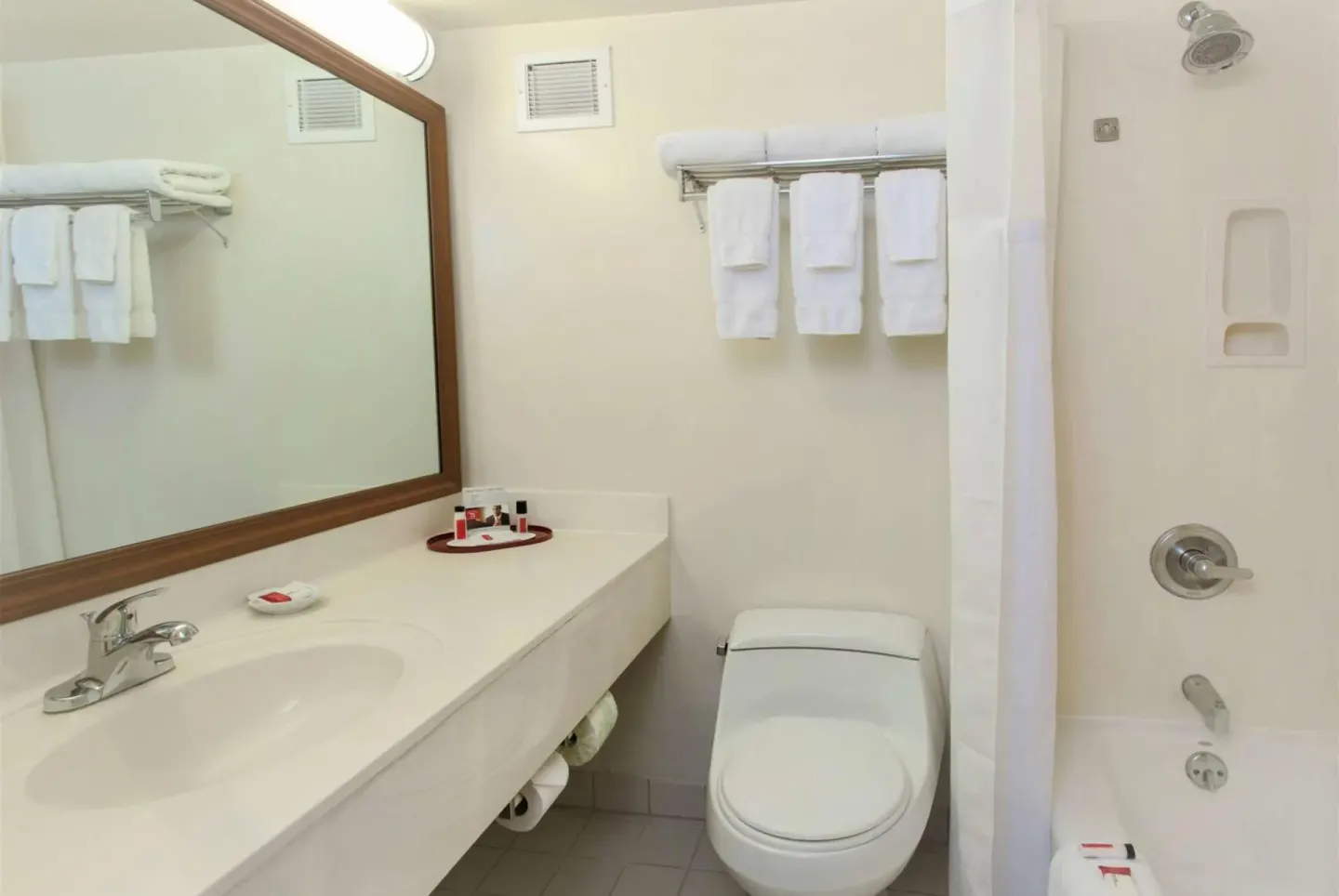 Bathroom with vanity, towels, and shower-tub at Ramada Plaza Waikiki.