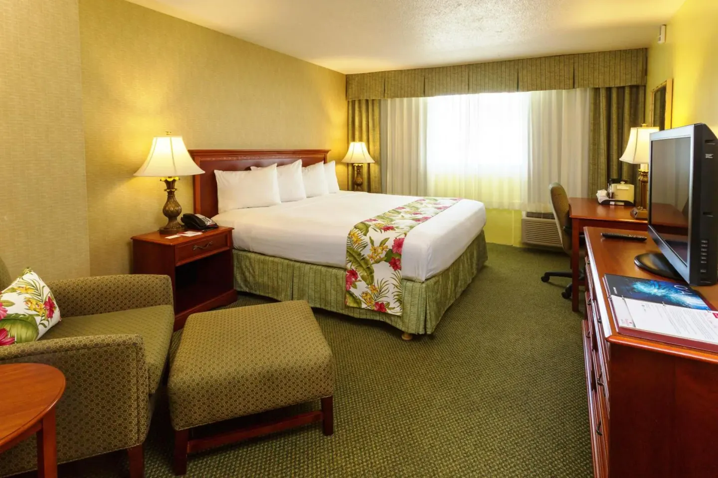 King bed guest room with desk and armchair at Ramada Plaza Waikiki.