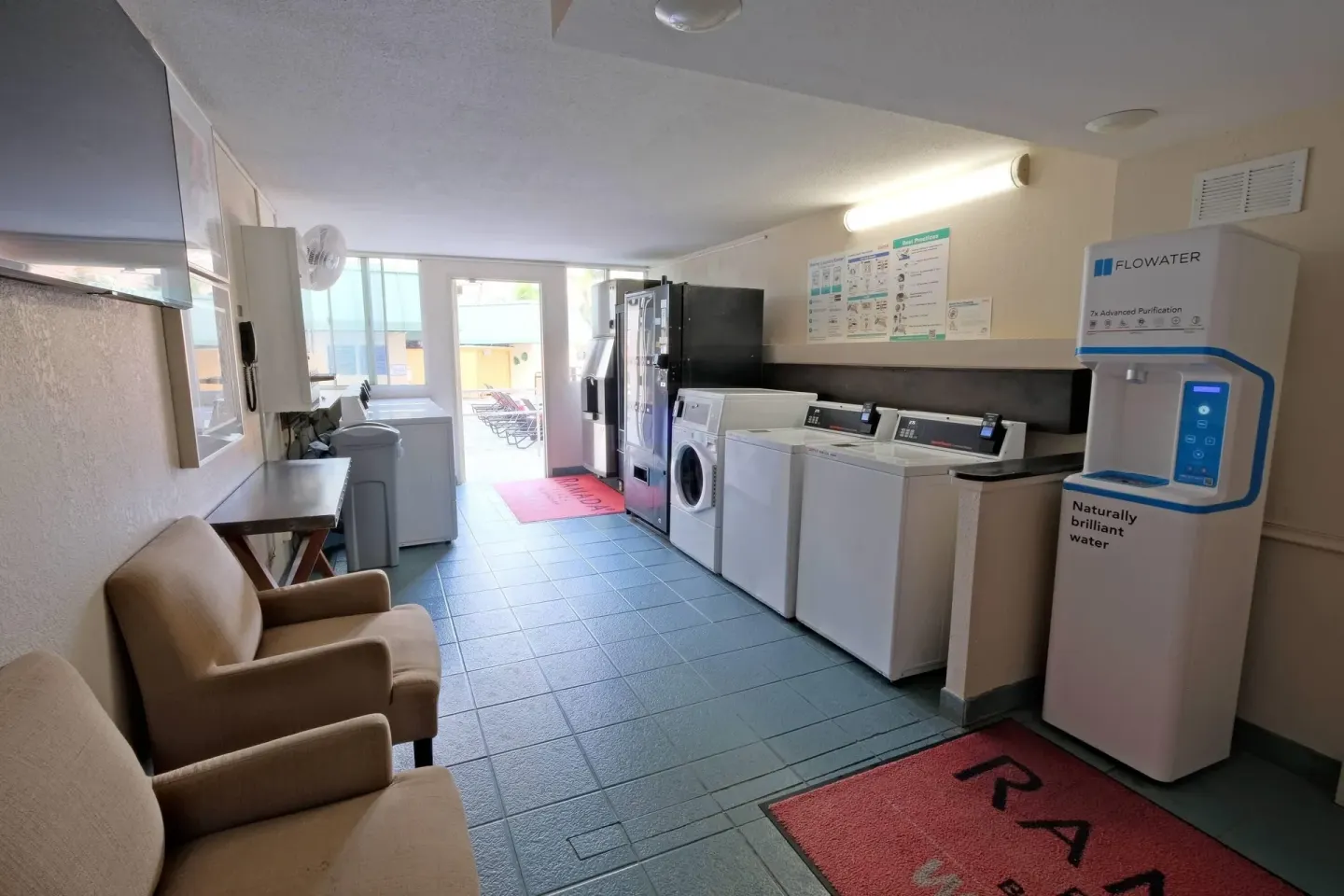 Laundry room with washers, vending machines, seating, and water station at Ramada Plaza Waikiki.