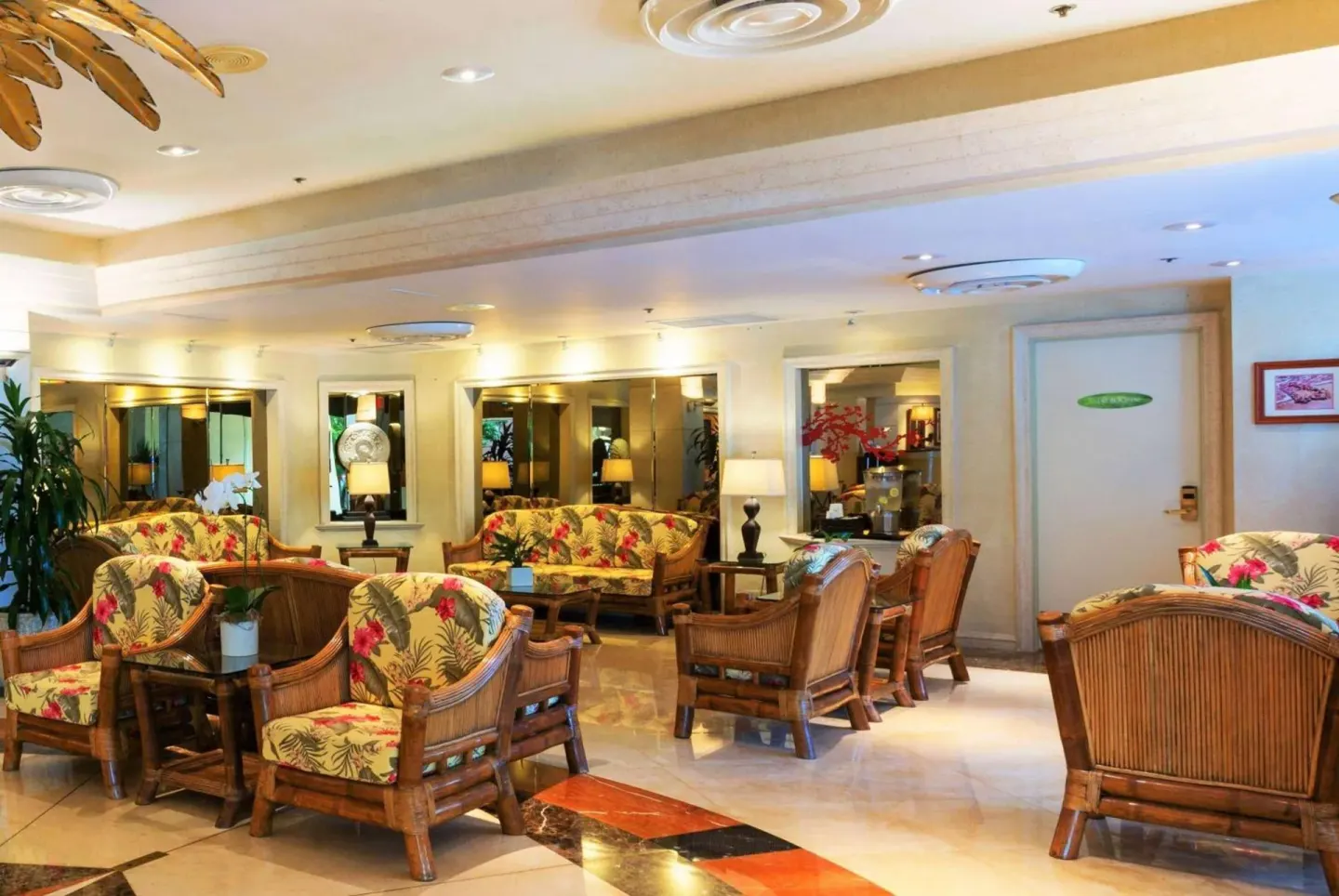 Lobby seating area with tropical-print wicker furniture at Ramada Plaza Waikiki.