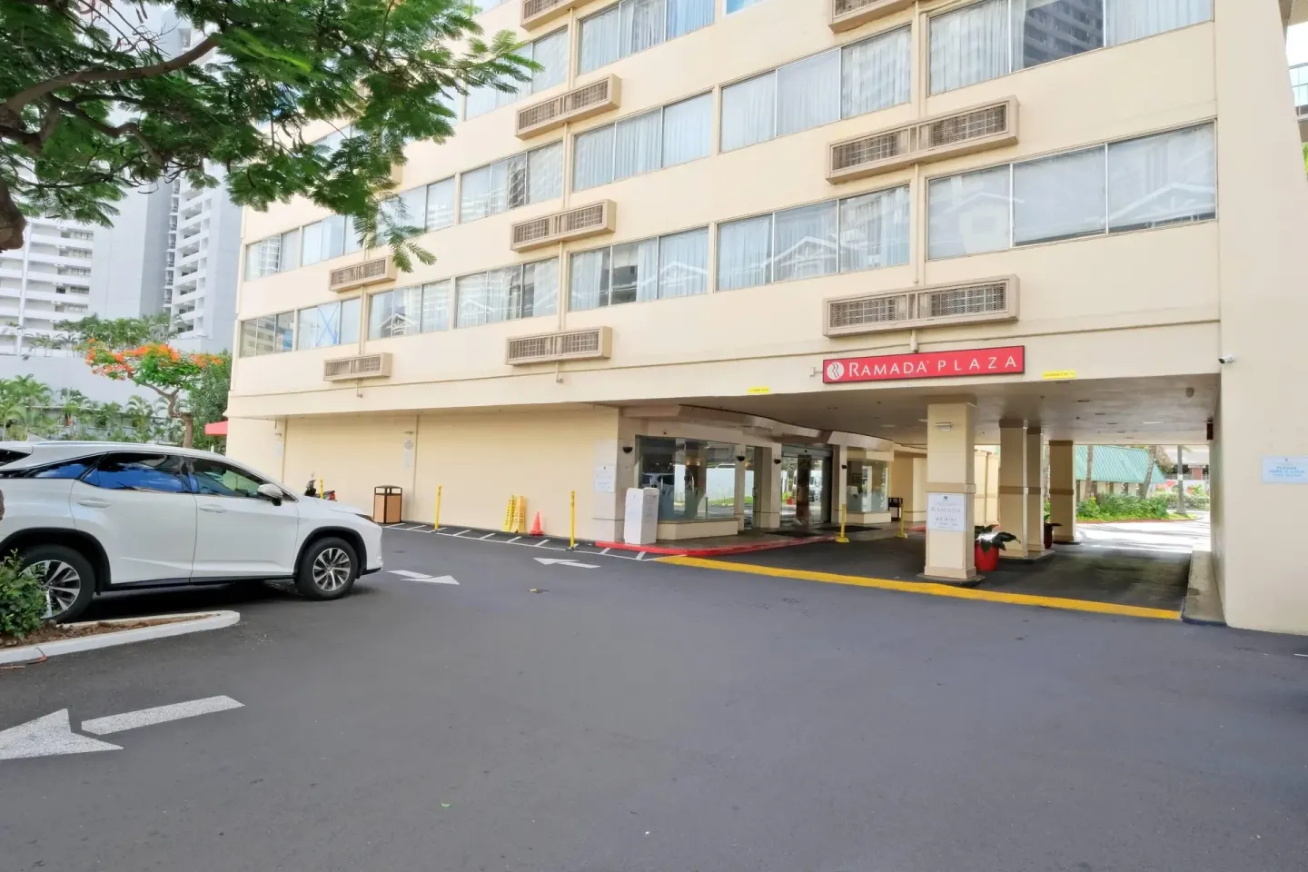 Driveway and covered porte cochere at Ramada Plaza Waikiki with a red hotel sign above.