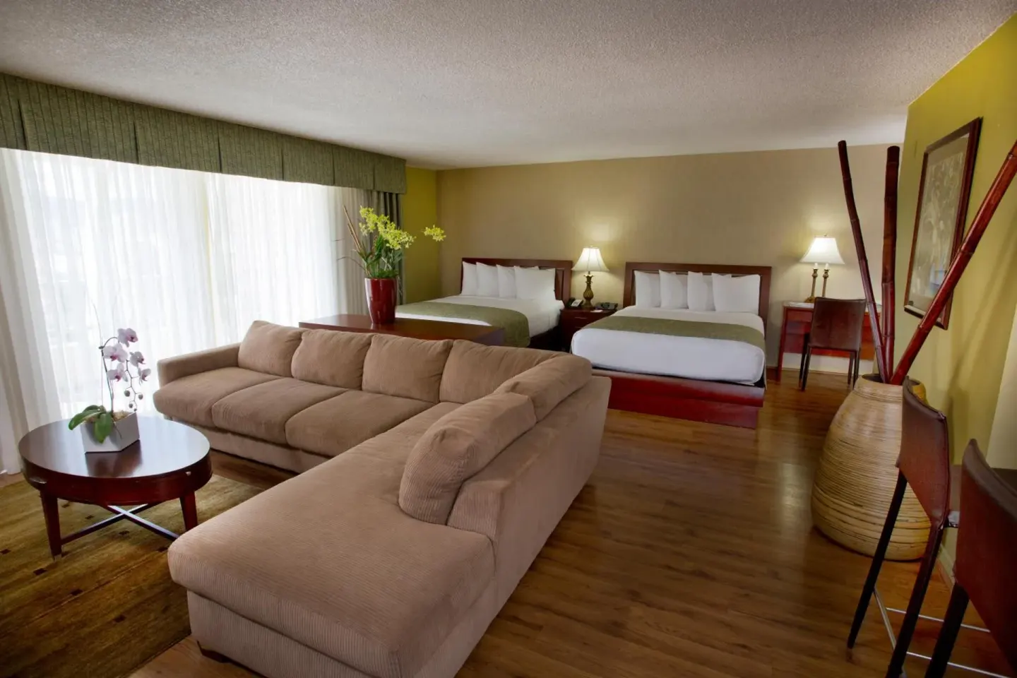Suite with two beds and a sectional sofa at Ramada Plaza Waikiki.