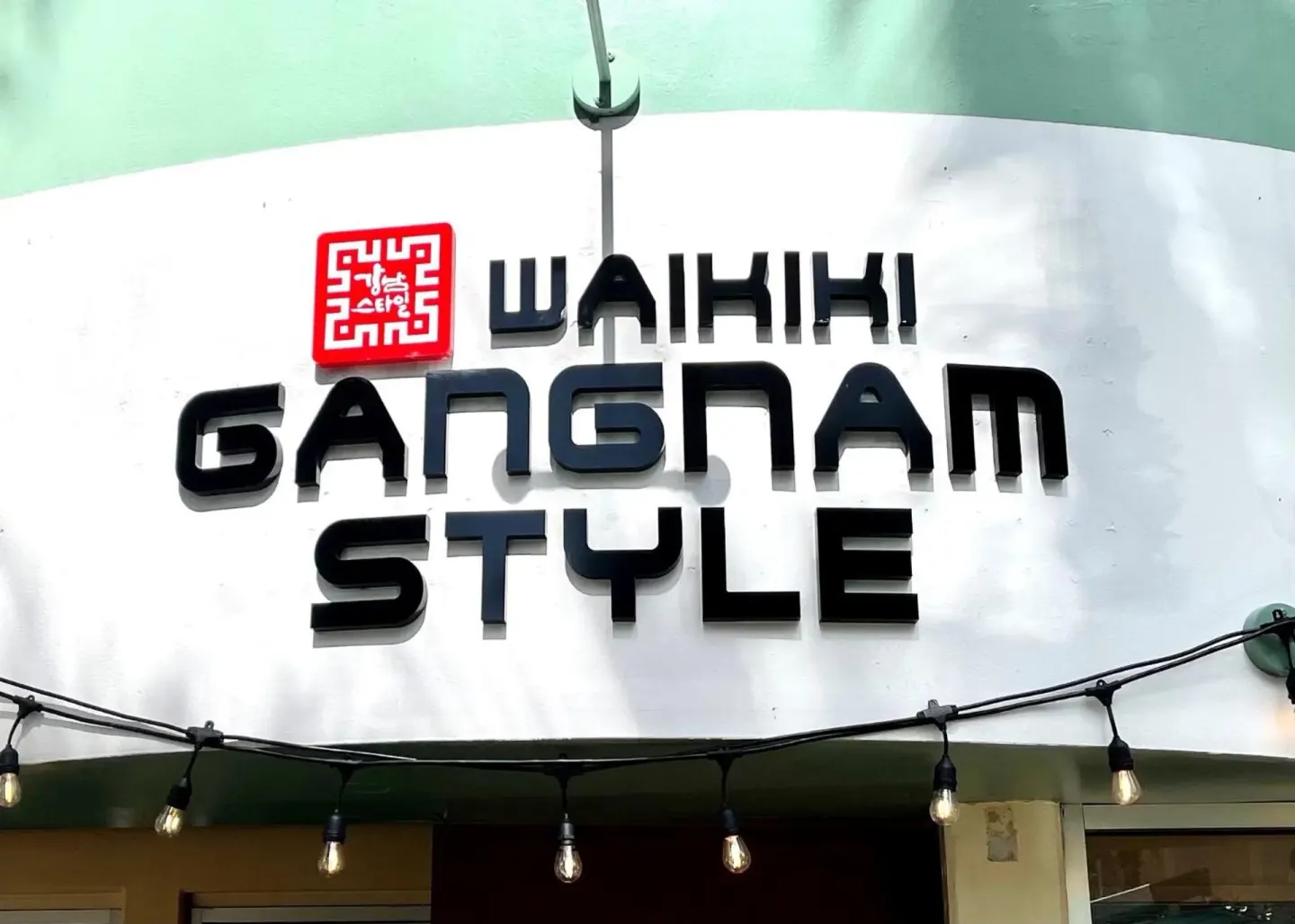 Waikiki Gangnam Style exterior sign with string lights at Ramada Plaza Waikiki.