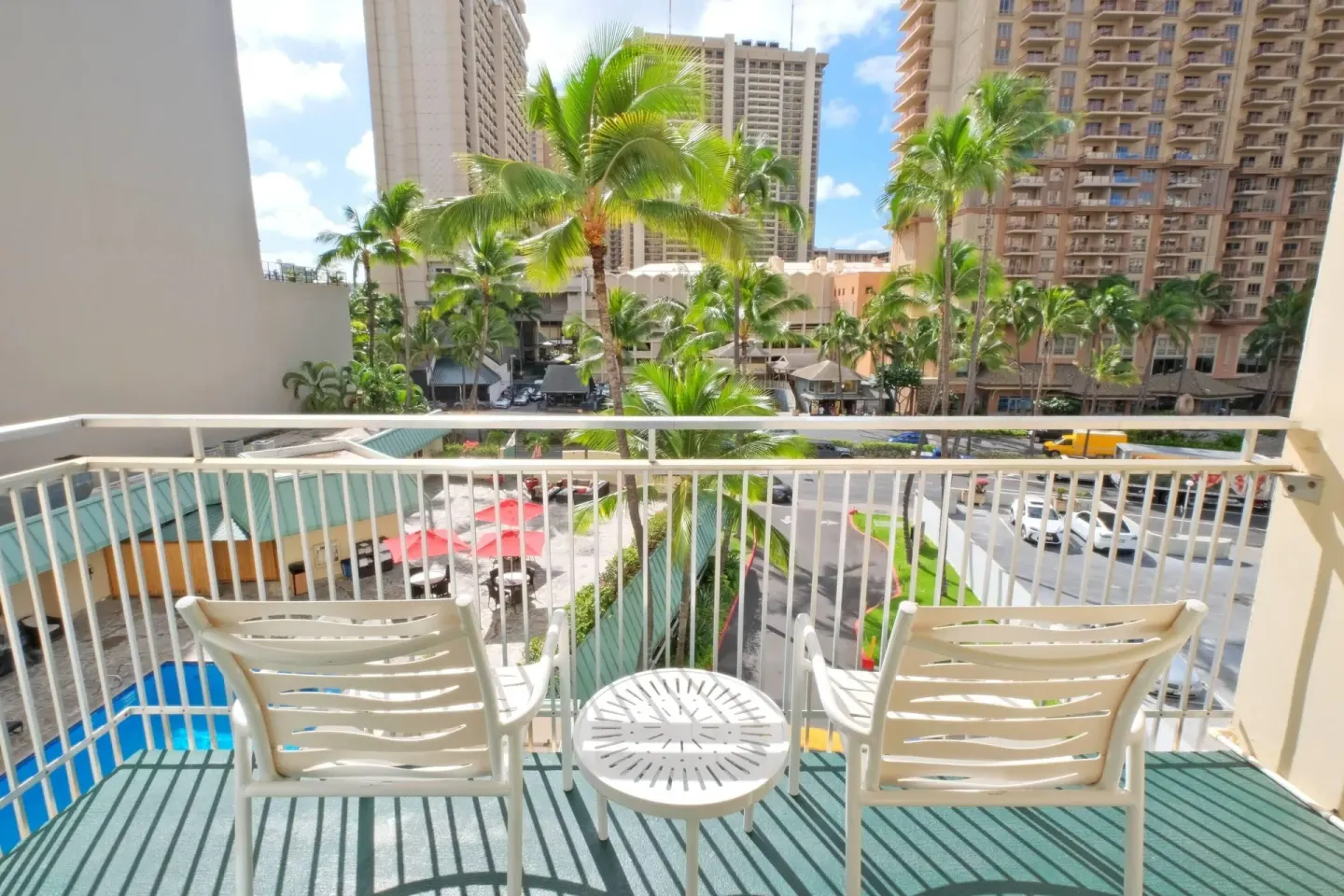 Balcony seating with palm trees and city buildings at Ramada Plaza Waikiki.