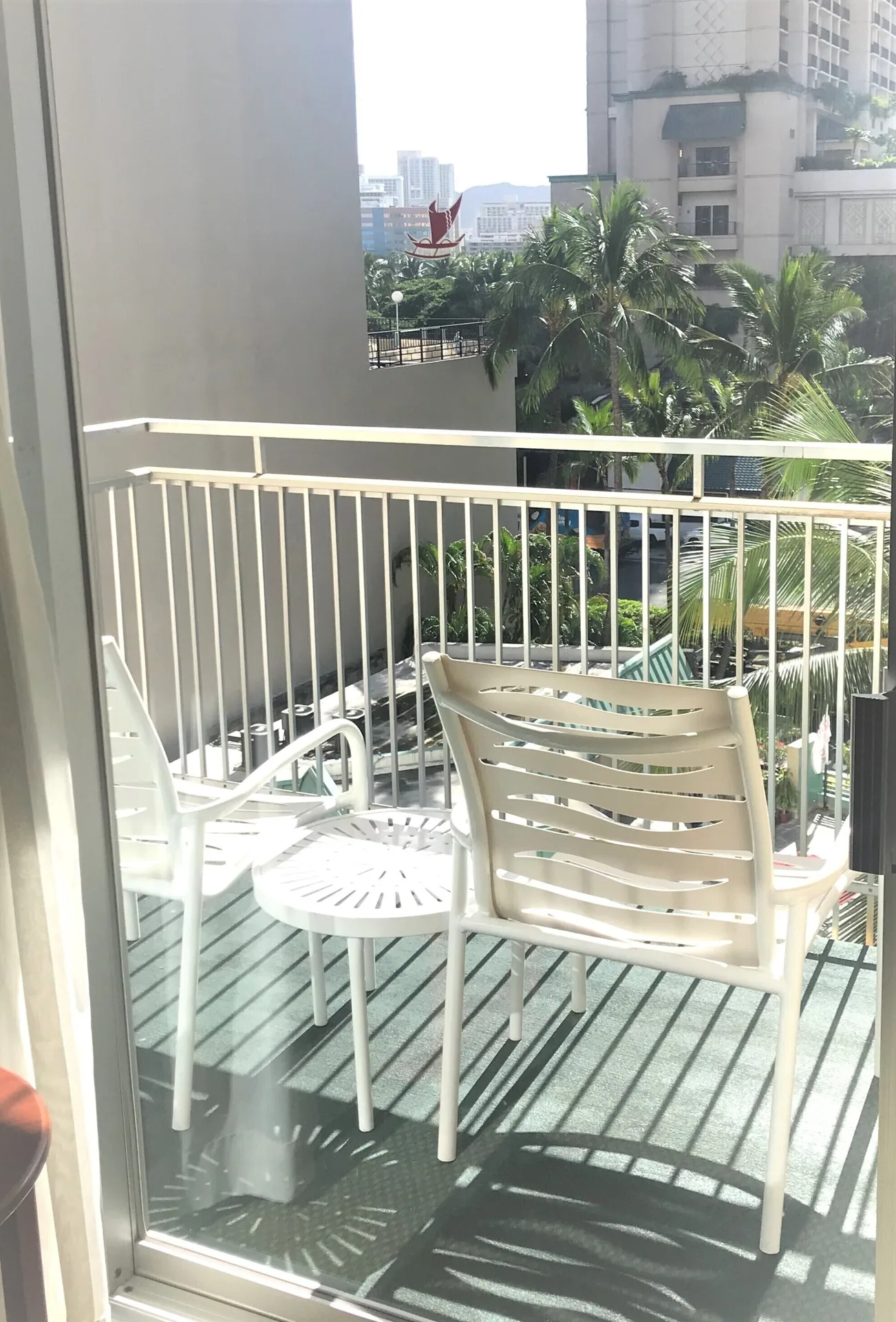 Balcony chairs and table seen through a sliding door at Ramada Plaza Waikiki.