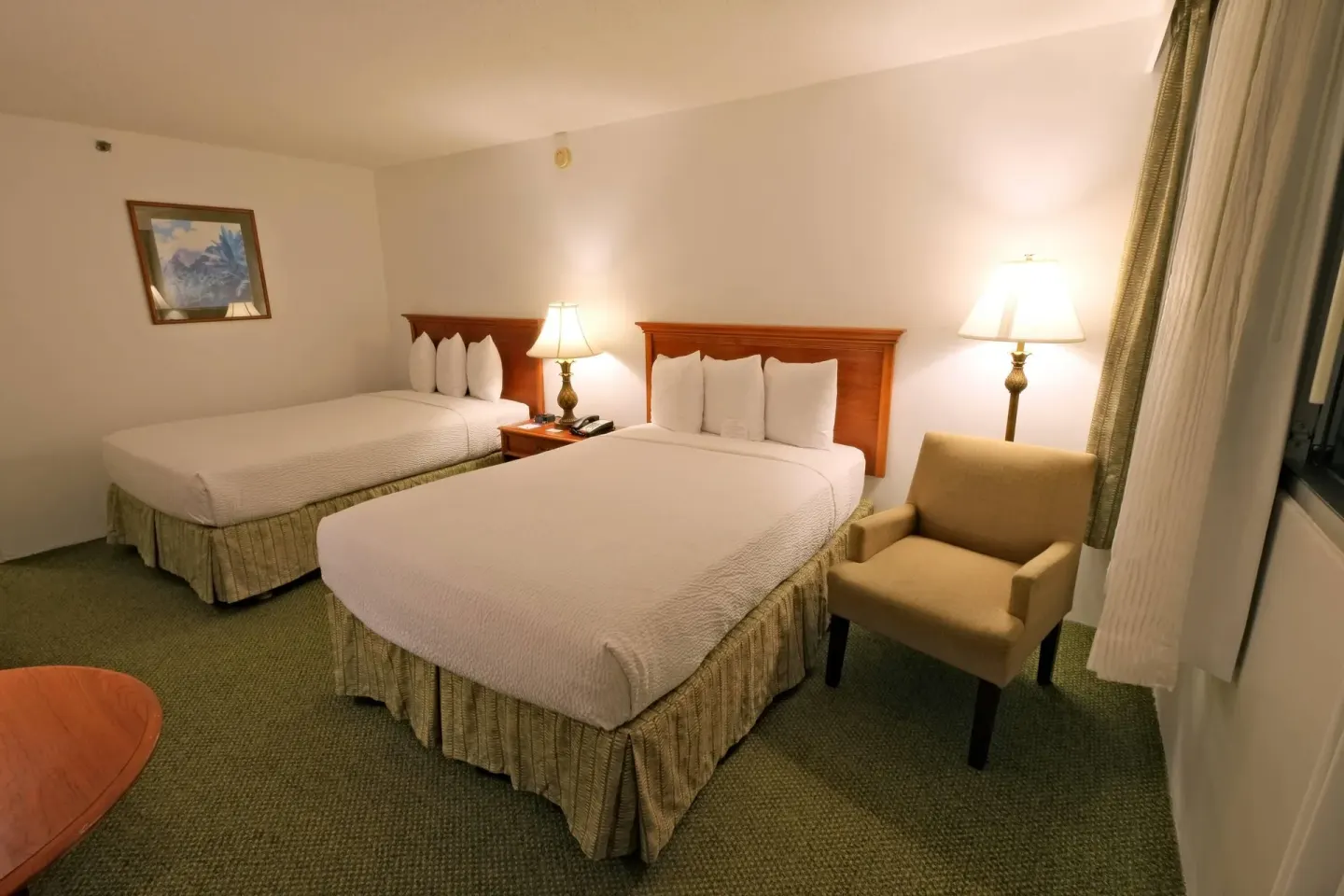 Two-bed guest room with armchair and bedside lamps at Ramada Plaza Waikiki.