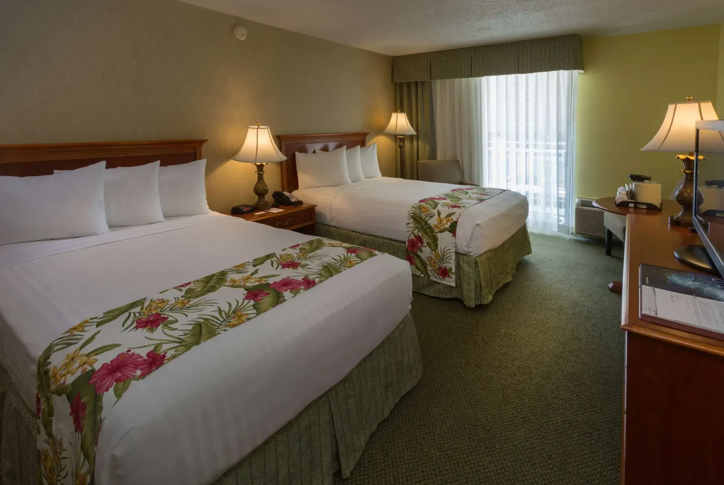 Two-bed balcony guest room with desk and lamps at Ramada Plaza Waikiki.