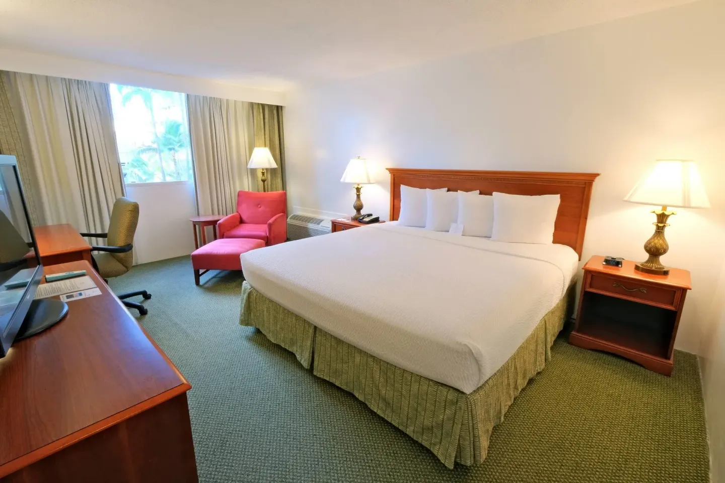 Non-smoking king room with red lounge chair and work desk at Ramada Plaza Waikiki.
