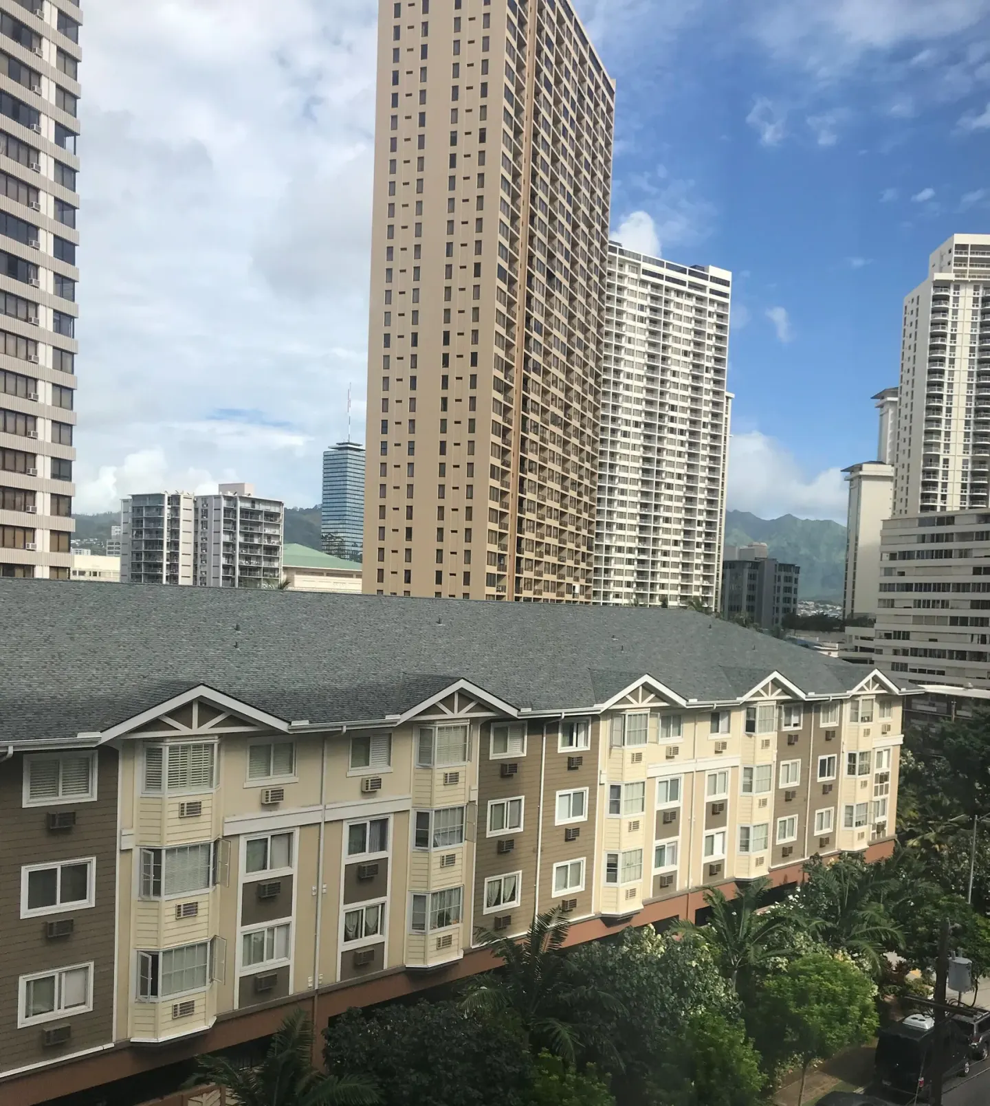 City view from a Standard Room at Ramada Plaza Waikiki with high-rise buildings and distant mountains.