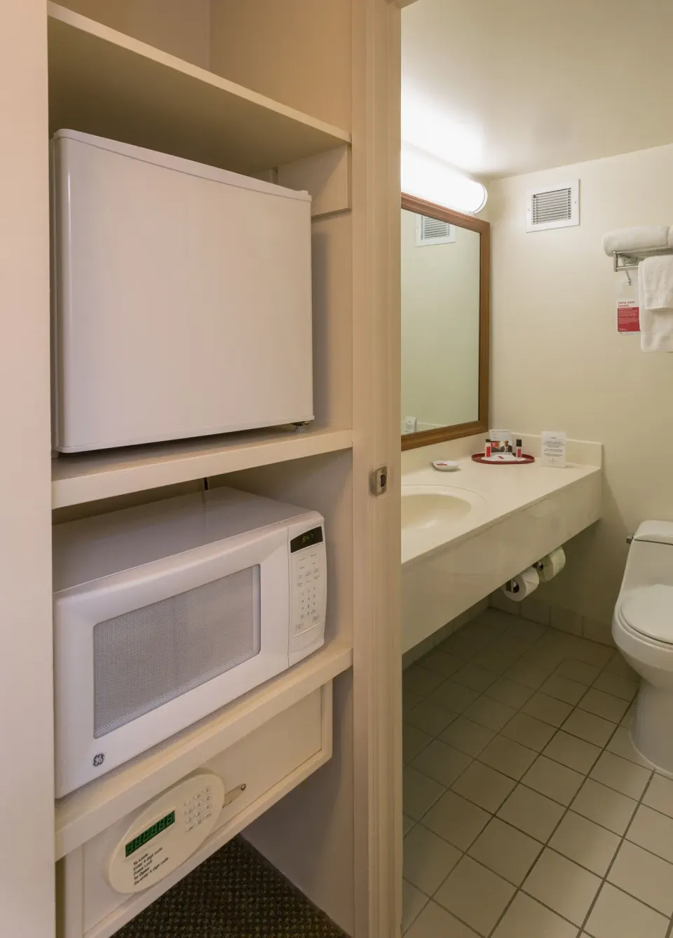 In-room refrigerator, microwave, safe and bathroom vanity in a Standard Room at Ramada Plaza Waikiki.