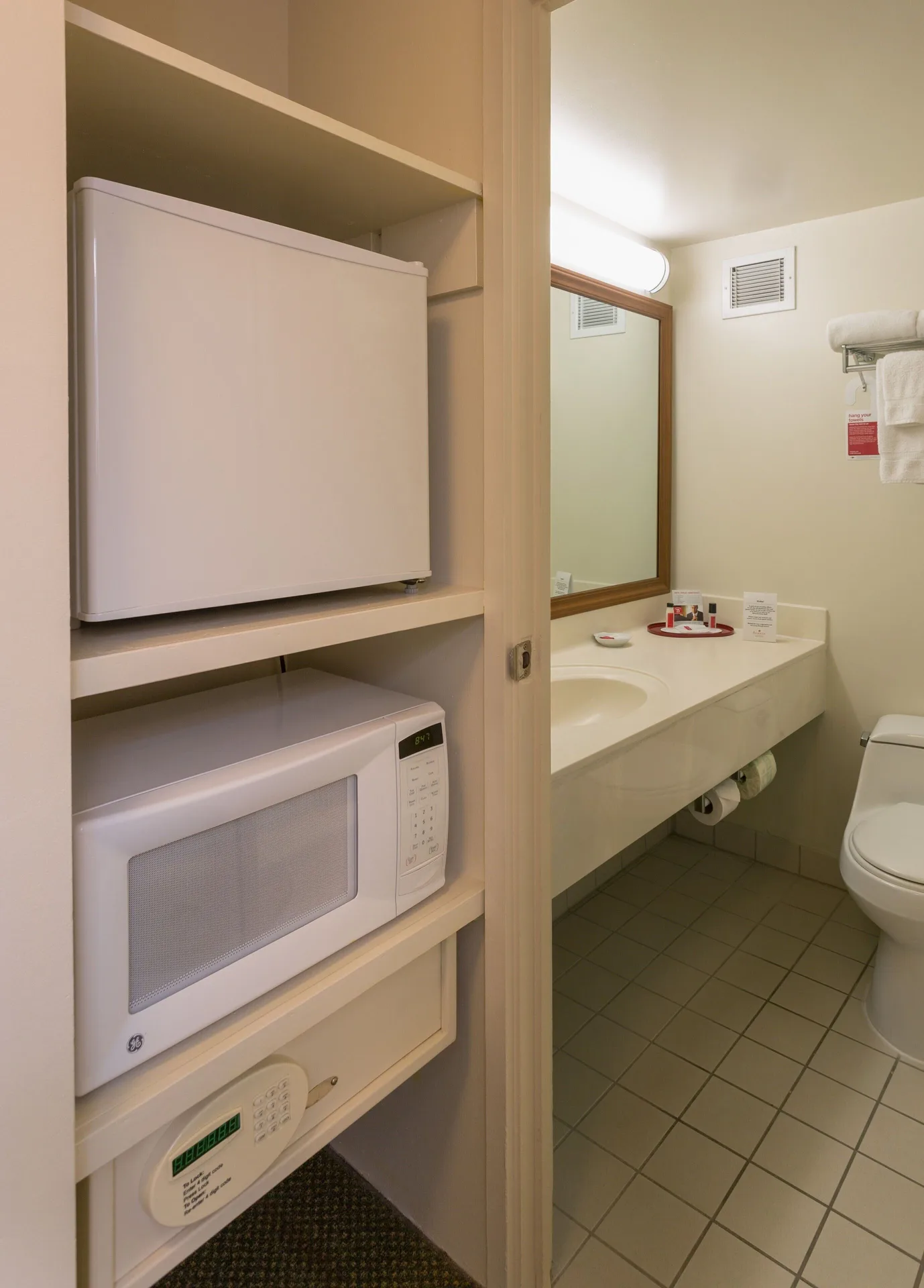 In-room refrigerator, microwave, safe and bathroom vanity in a Standard Room at Ramada Plaza Waikiki.