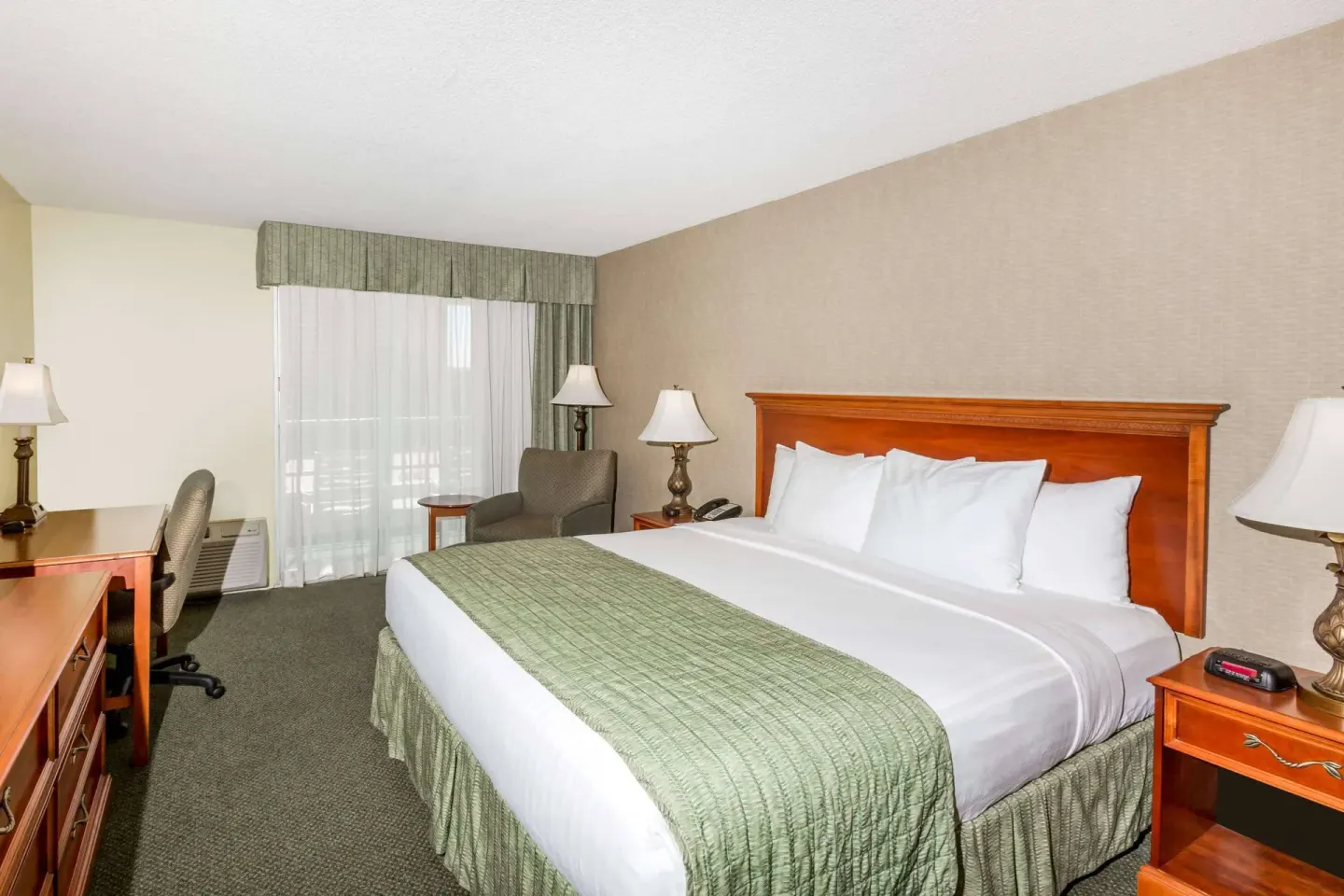 Standard Room with one king bed, desk, chair and window at Ramada Plaza Waikiki.
