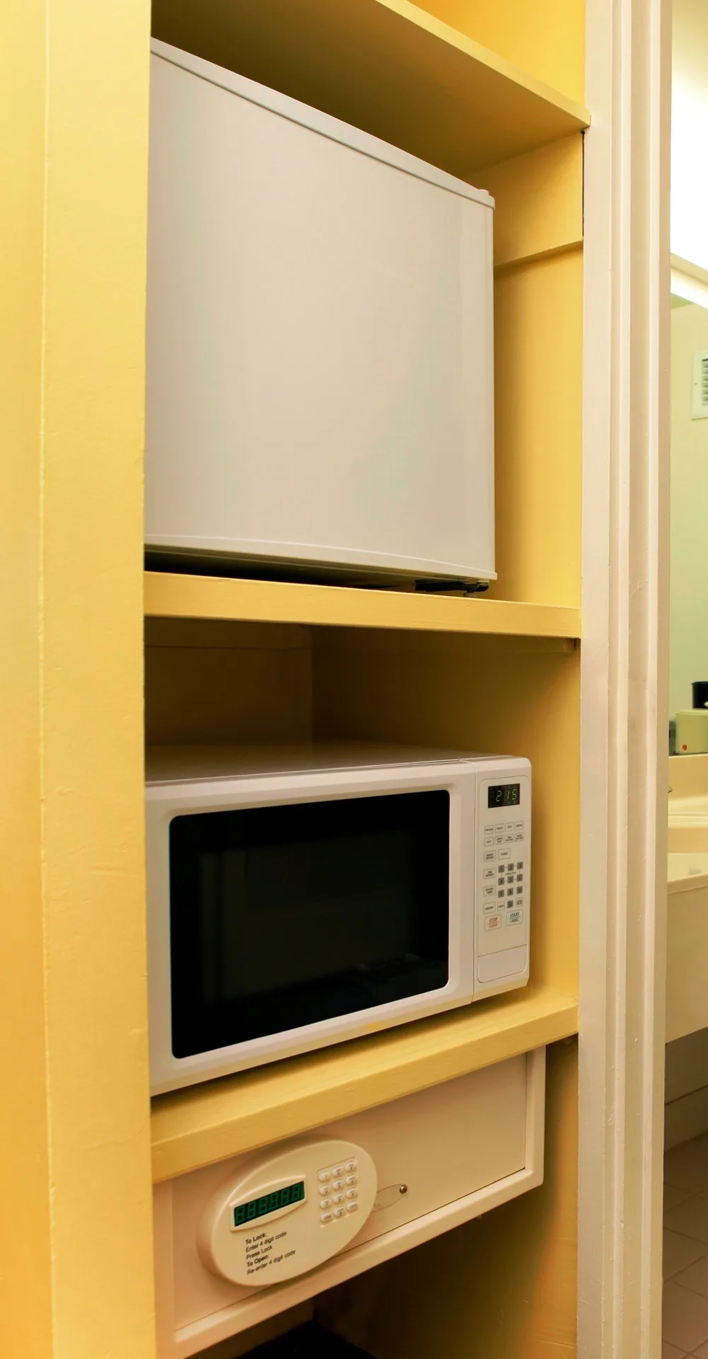 Close-up of in-room refrigerator, microwave and safe shelving at Ramada Plaza Waikiki.