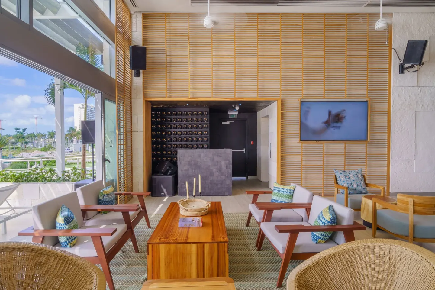 Bright lounge with armchairs and a wall-mounted TV at Renaissance Cancun Resort & Marina.