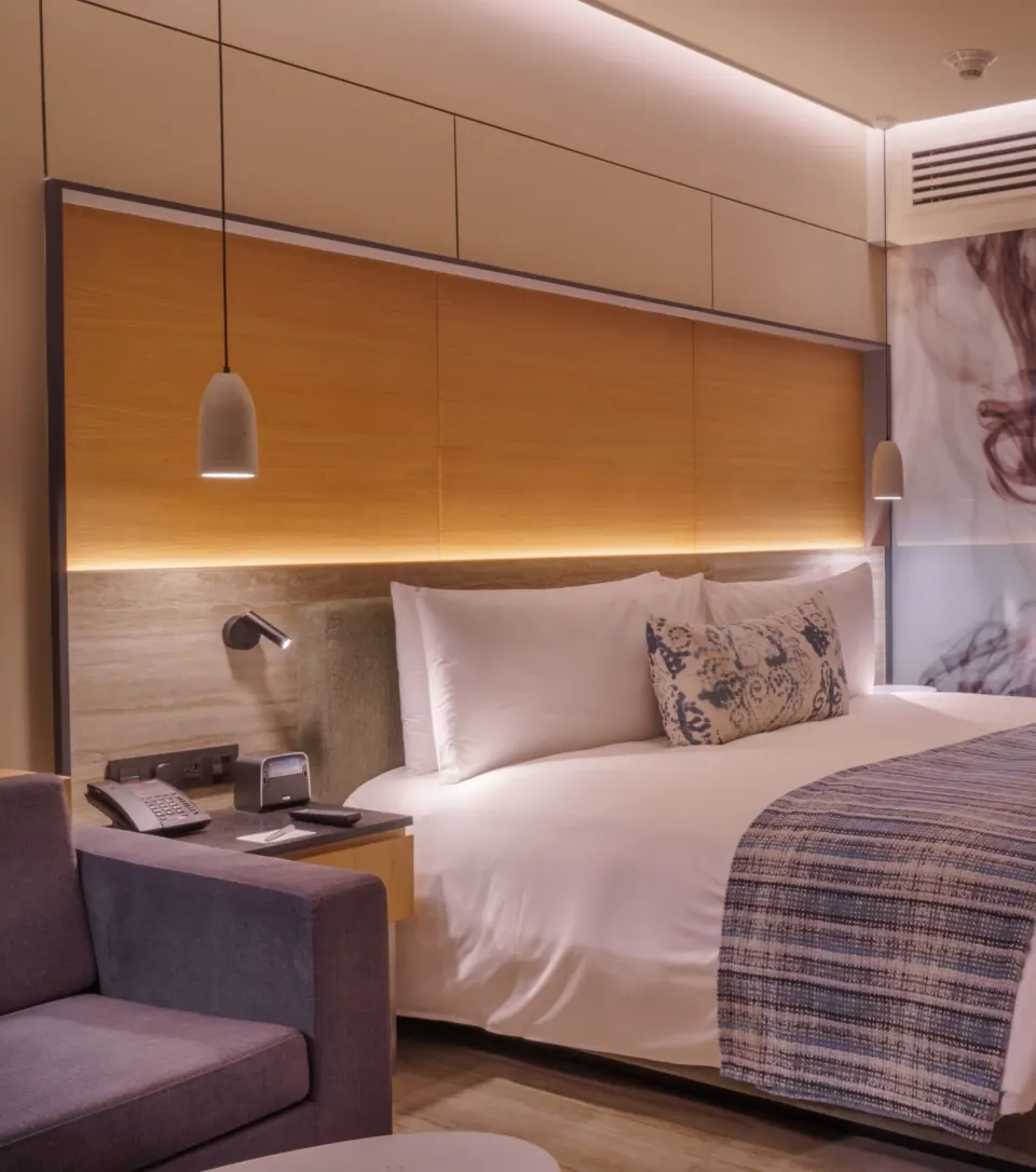 Guest room king bed at Renaissance Cancun Resort & Marina with pendant lights and a lounge chair.