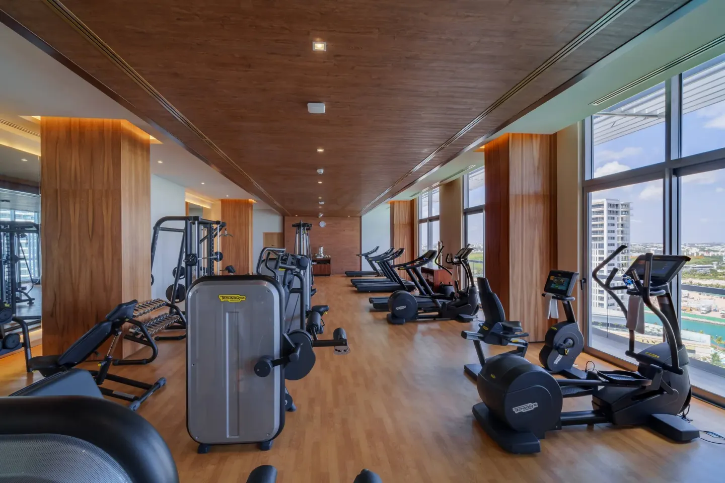 Gym with cardio machines, weights and tall windows at Renaissance Cancun Resort & Marina.