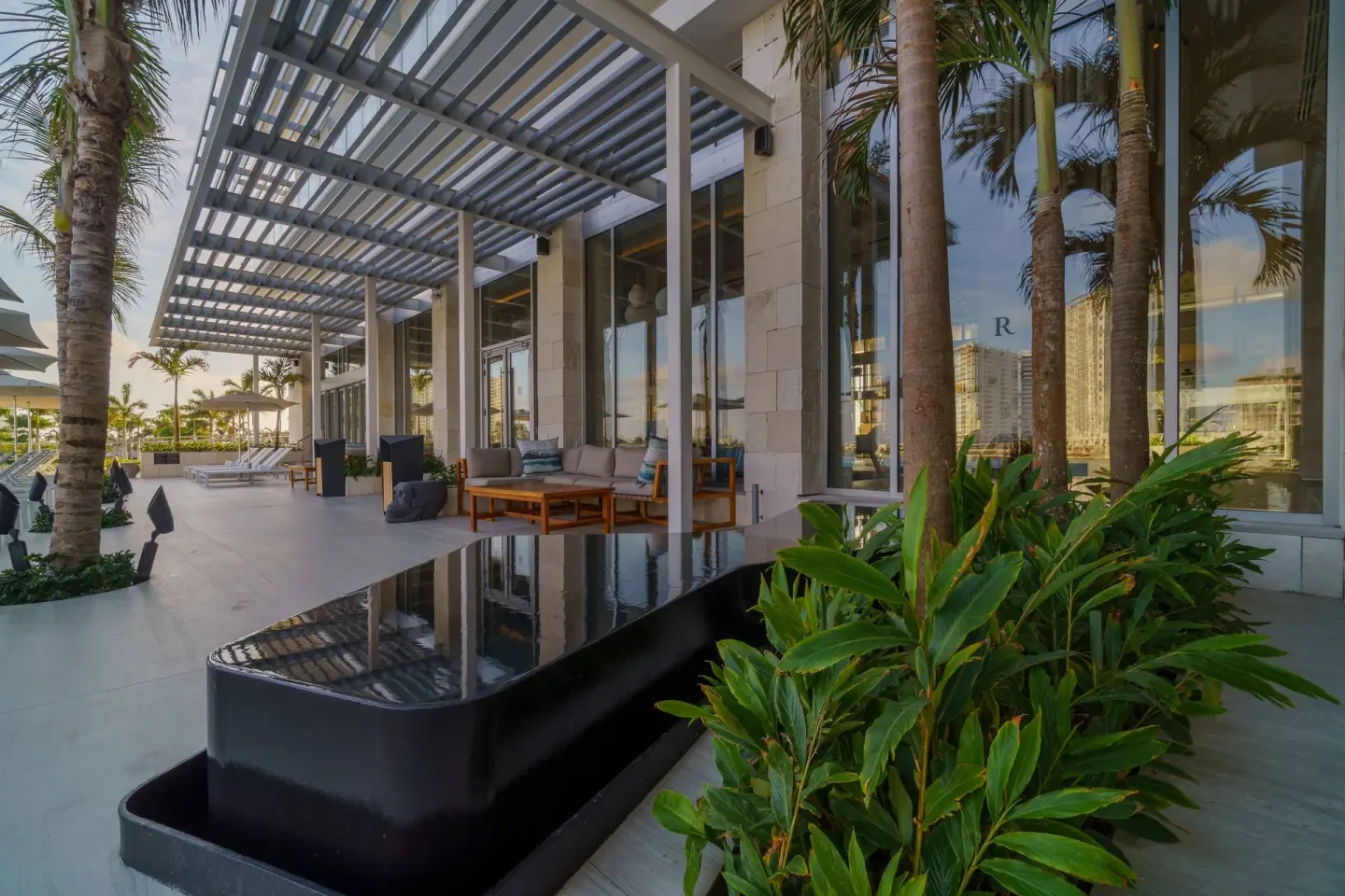 Outdoor terrace seating at Renaissance Cancun Resort & Marina beside palms and a black water feature.