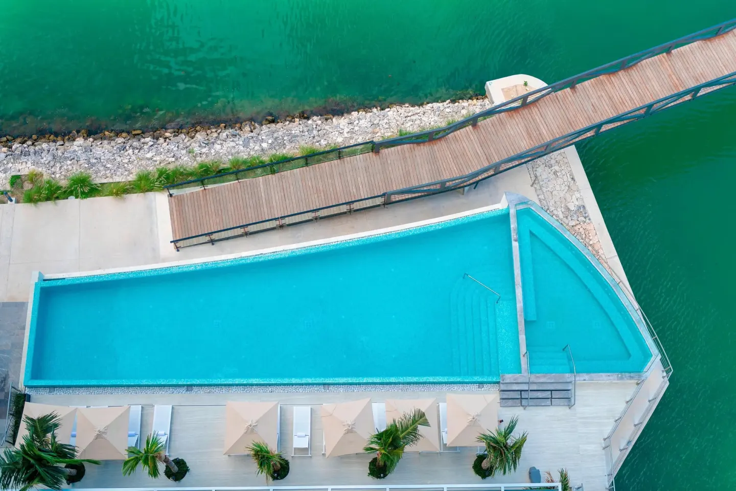 Overhead view of the pool at Renaissance Cancun Resort & Marina beside a curved bridge and marina water.