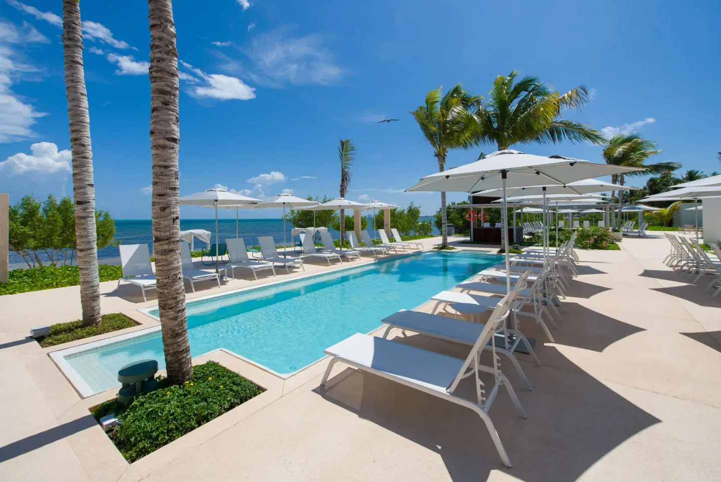 Pool deck with loungers, umbrellas, and ocean view at Renaissance Cancun Resort & Marina.