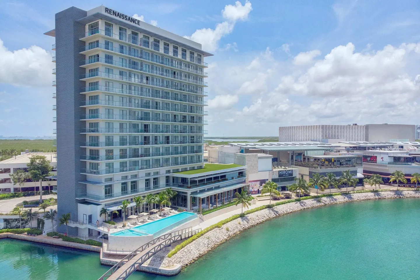 Aerial exterior view of Renaissance Cancun Resort & Marina beside turquoise water and a pool.
