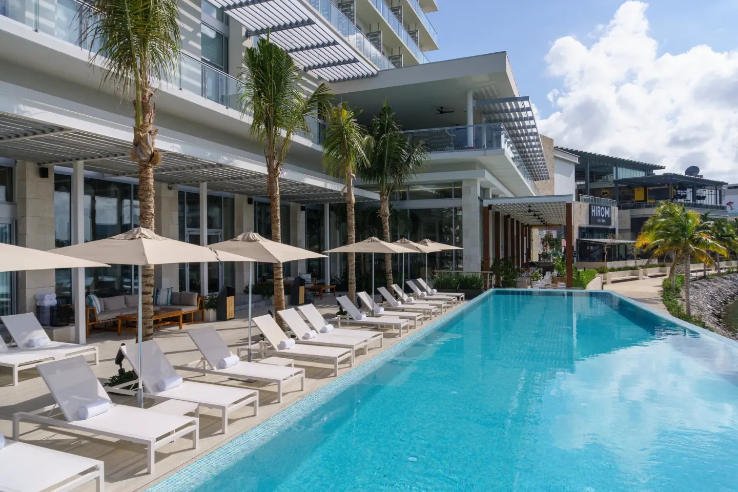 Swimming pool at Renaissance Cancun Resort & Marina lined with white loungers and umbrellas.