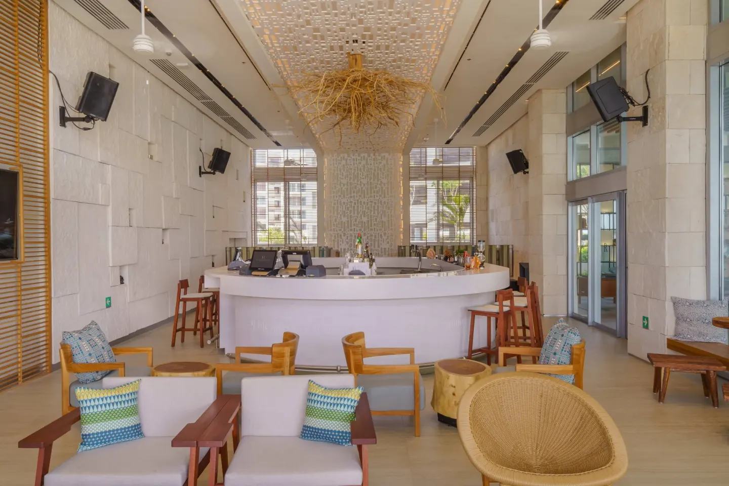 Bright bar lounge with curved counter and armchairs at Renaissance Cancun Resort & Marina.