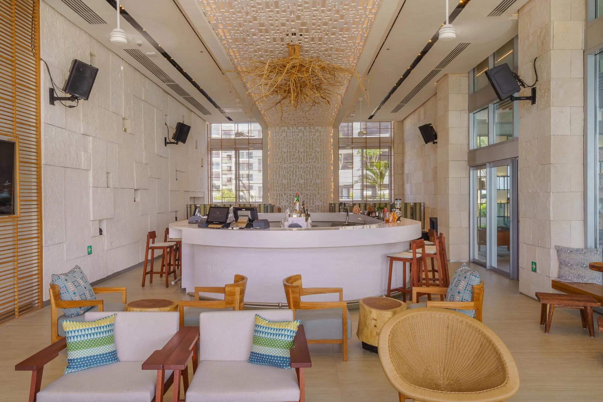 Bright bar lounge with curved counter and armchairs at Renaissance Cancun Resort & Marina.