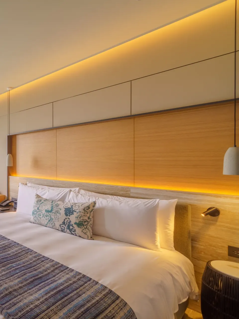King bed and illuminated wood headboard in a deluxe room at Renaissance Cancun Resort & Marina.