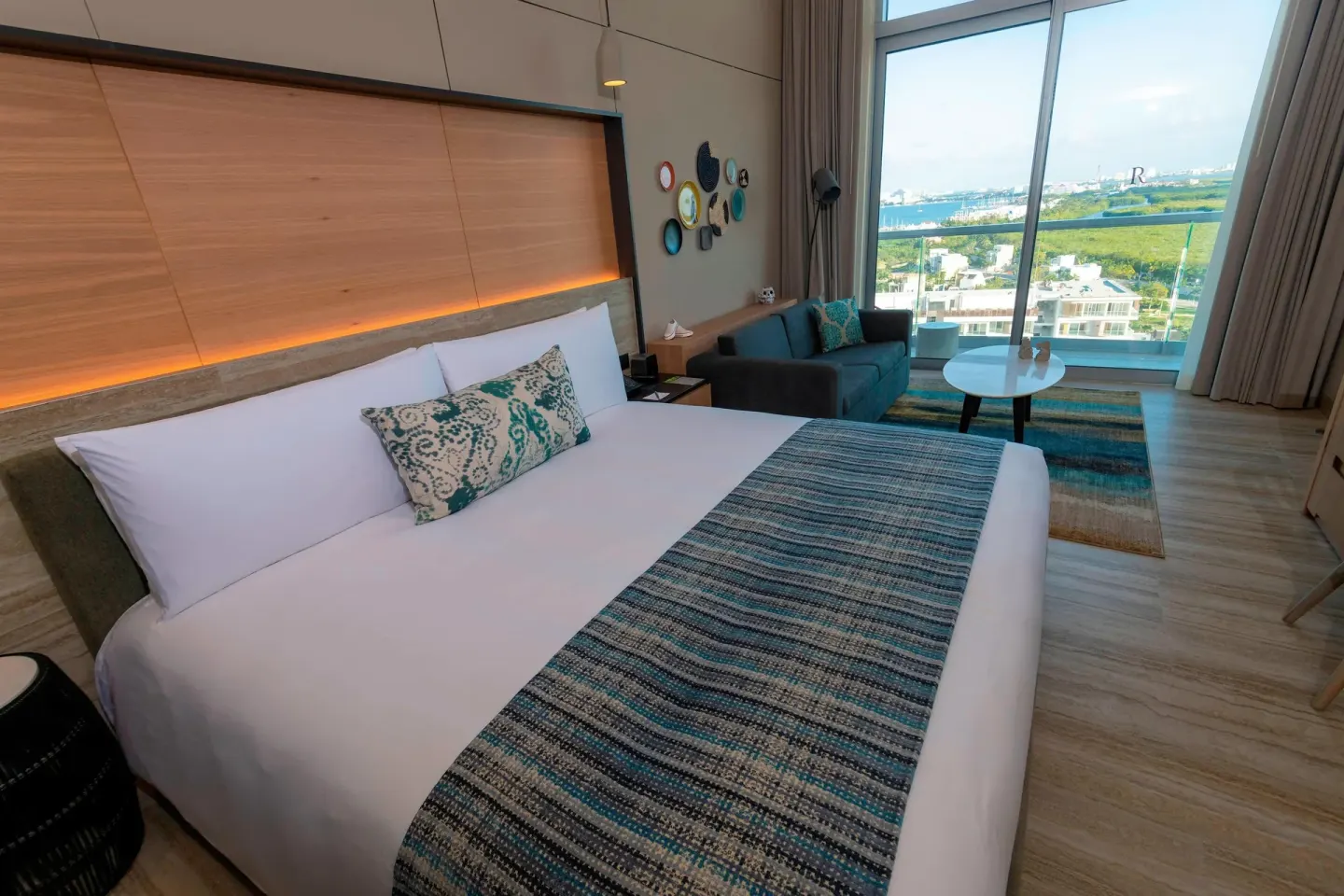 King-bed ocean-view room with sofa by tall windows at Renaissance Cancun Resort & Marina.