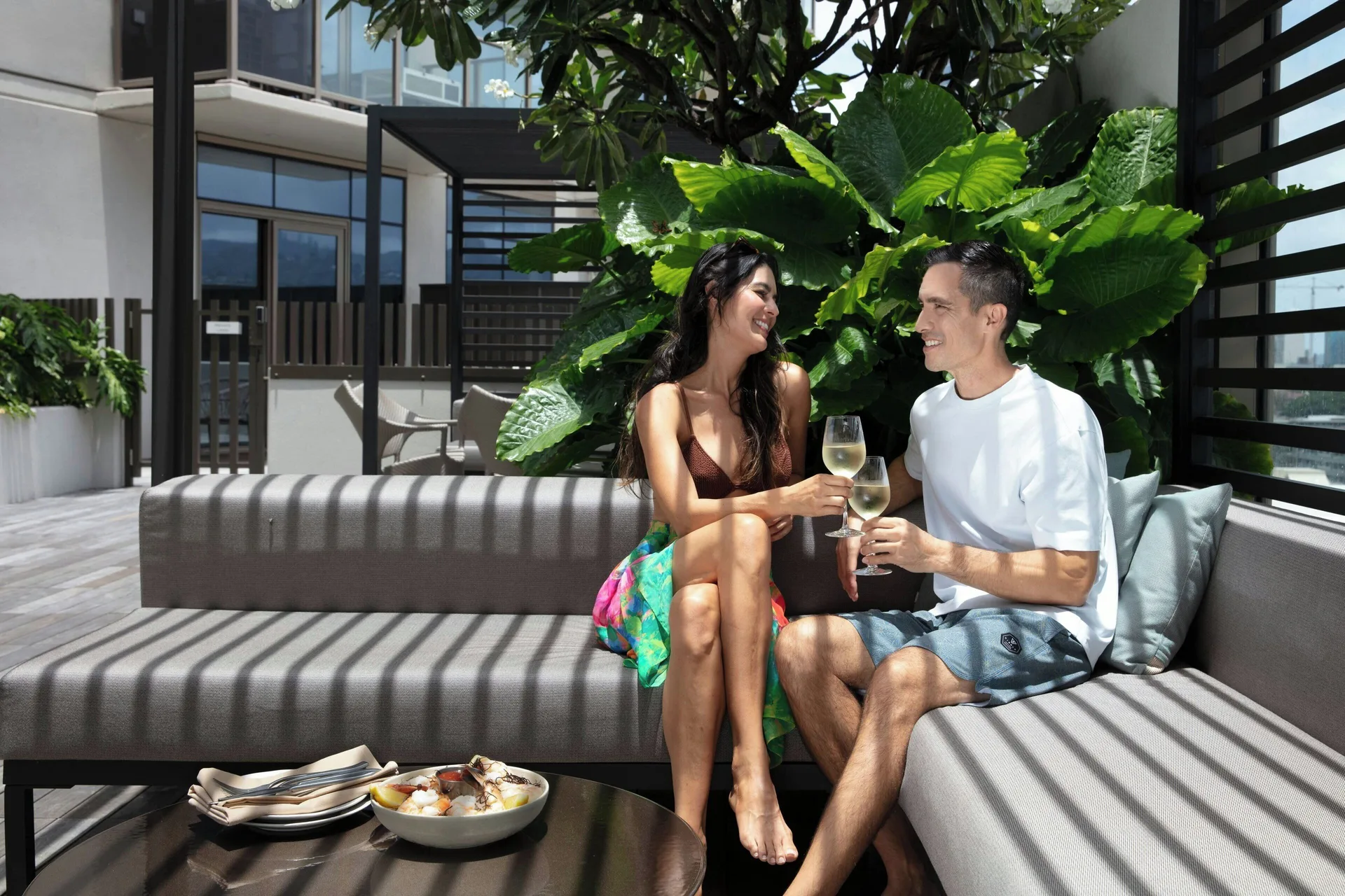 Guests toast with drinks on an outdoor lounge terrace at Renaissance Honolulu Hotel & Spa.