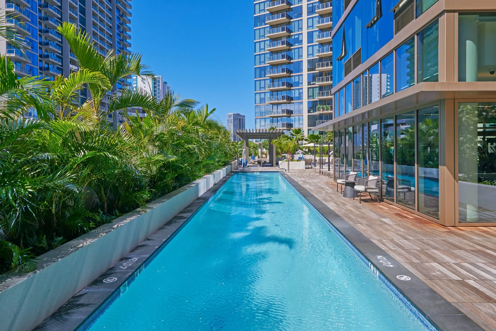 Rooftop lap pool beside palms and glass towers at Renaissance Honolulu Hotel & Spa.