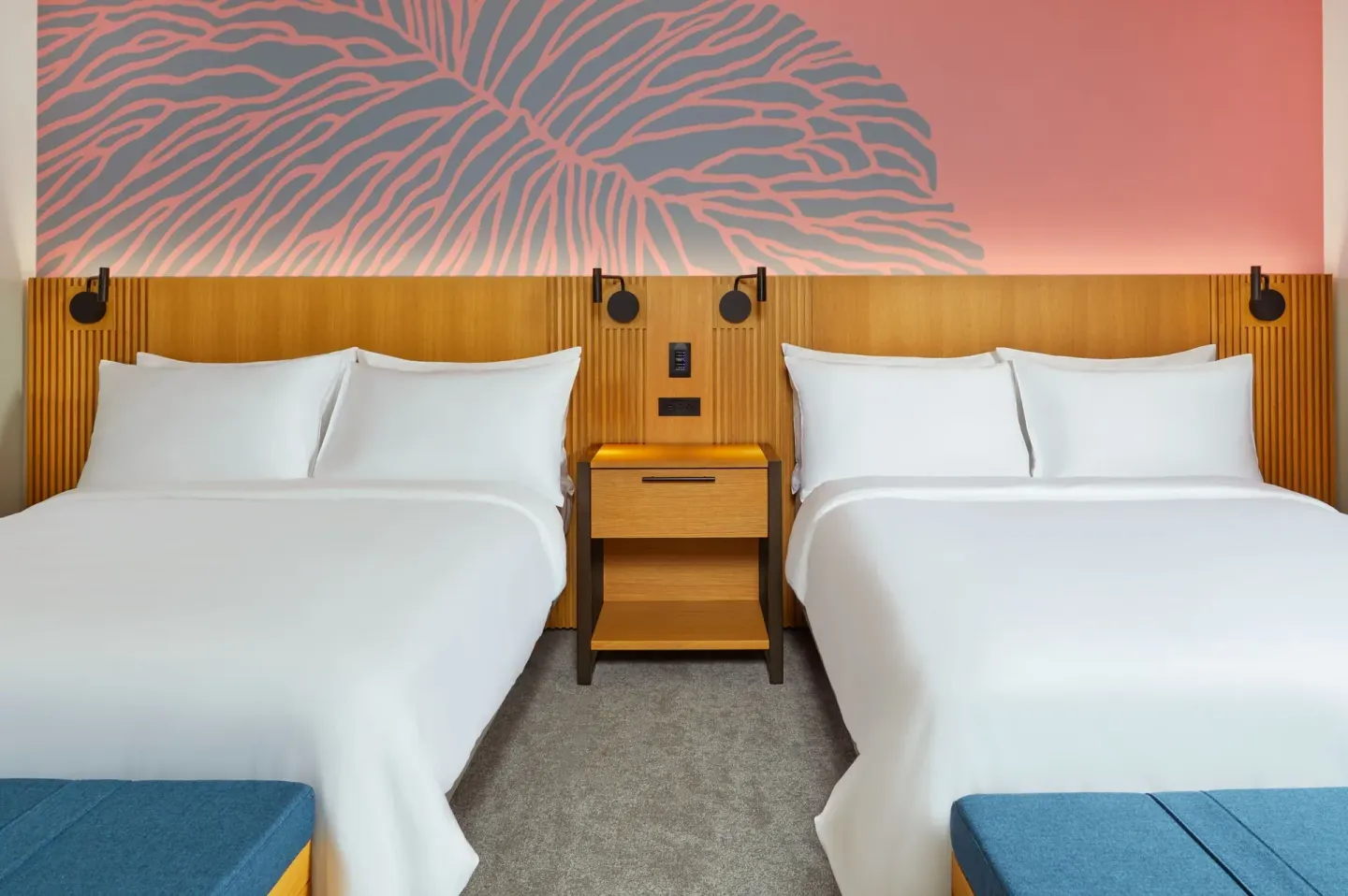 Two white beds in a City View room at Renaissance Honolulu Hotel & Spa with pink mural lighting.