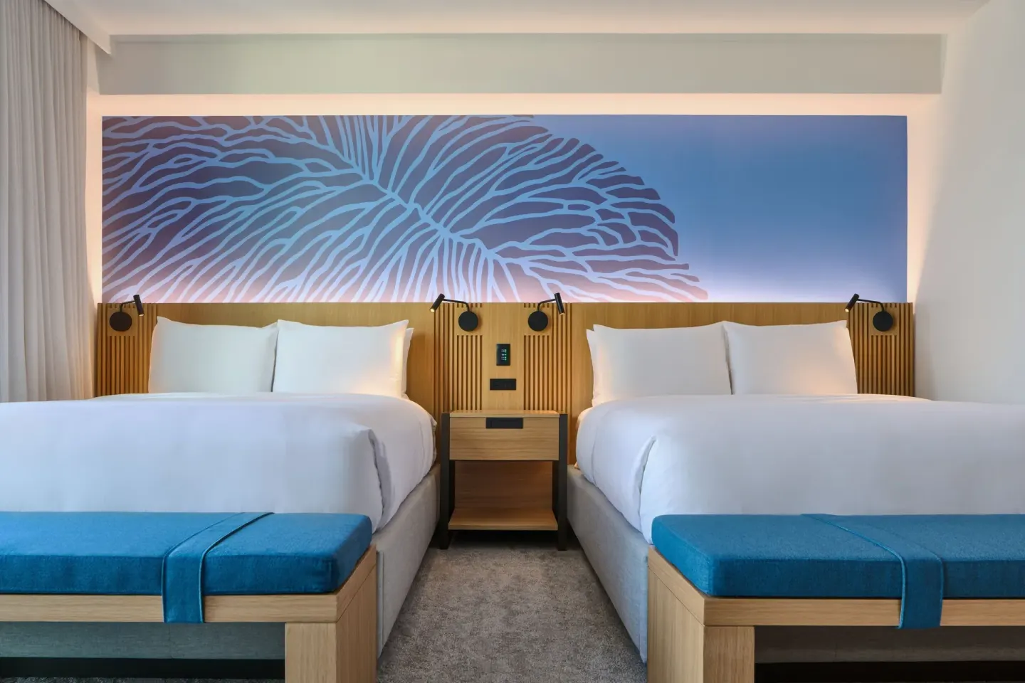 Two-bed City View guest room at Renaissance Honolulu Hotel & Spa with blue benches and mural headboard.