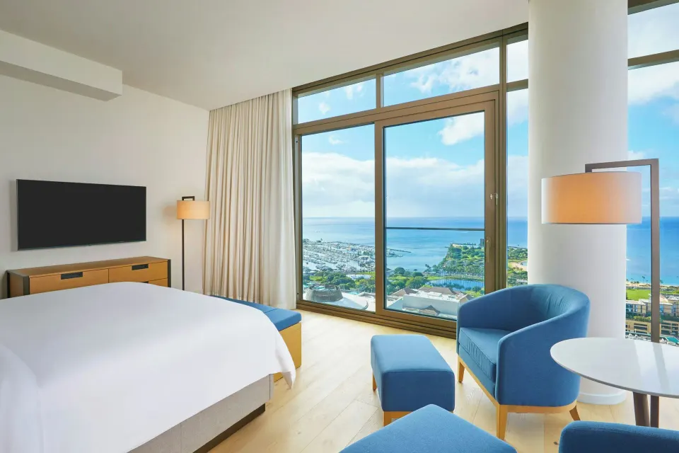 Bedroom in the Kaiului Penthouse suite at Renaissance Honolulu Hotel & Spa with ocean-view windows.