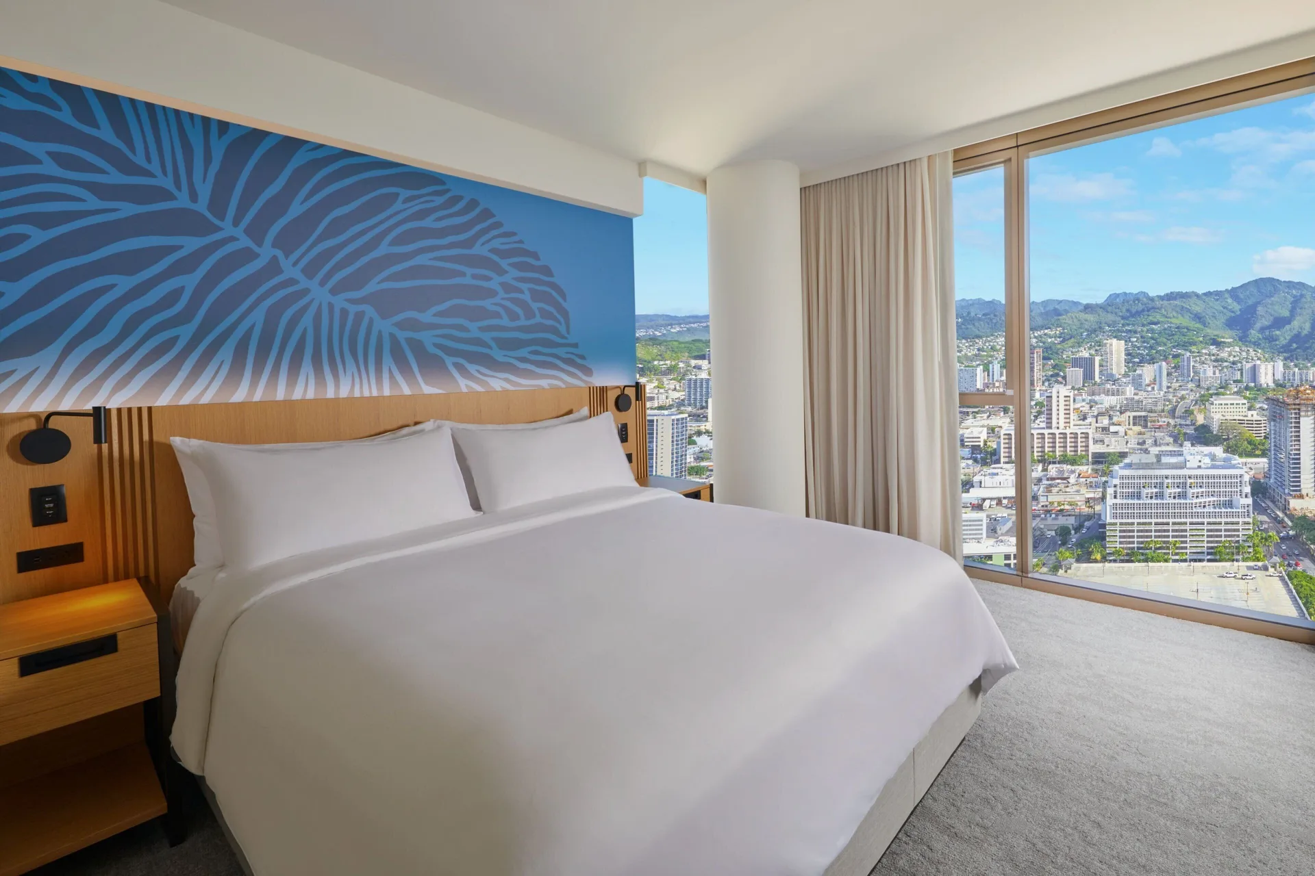 King bed beside floor-to-ceiling mountain-view windows at Renaissance Honolulu Hotel & Spa.