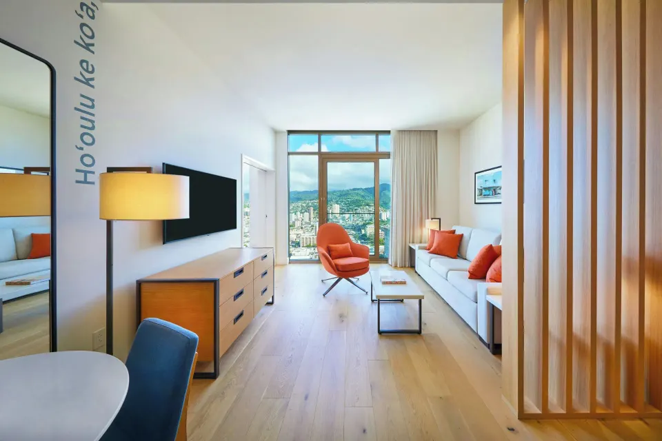 Suite living area with sofa, TV, and mountain-view windows at Renaissance Honolulu Hotel & Spa.