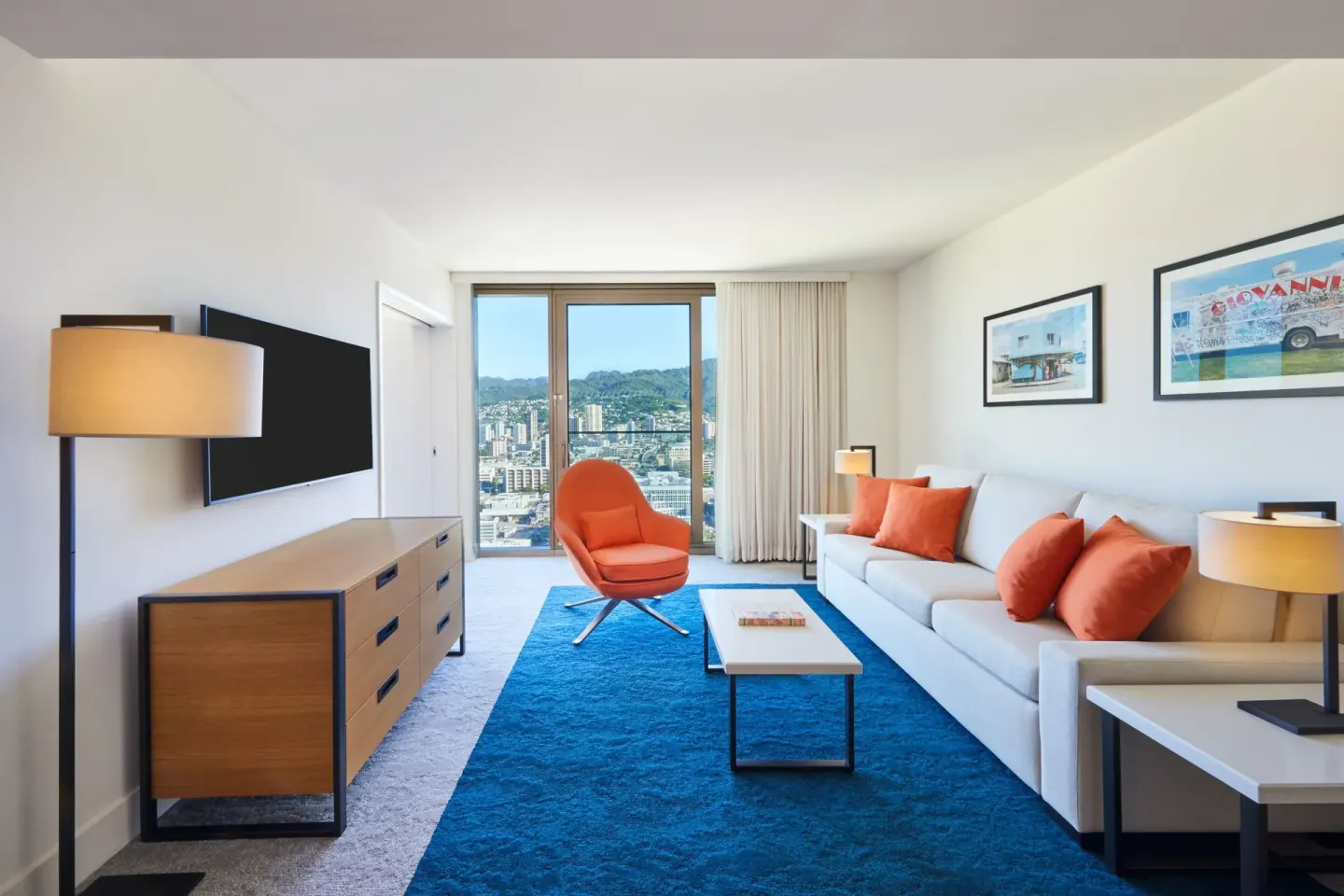 Living room with sofa, blue rug, and mountain view at Renaissance Honolulu Hotel & Spa.