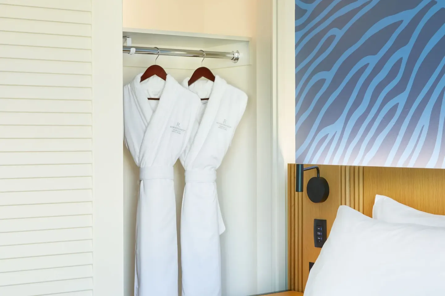 White robes hanging by the king bed in a suite at Renaissance Honolulu Hotel & Spa.