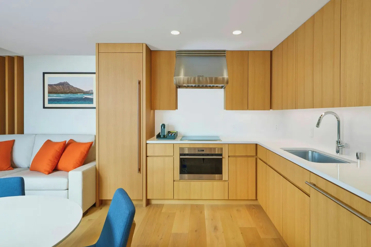 Kitchen in an Ocean View one-bedroom suite at Renaissance Honolulu Hotel & Spa with wood cabinets and sofa nearby.