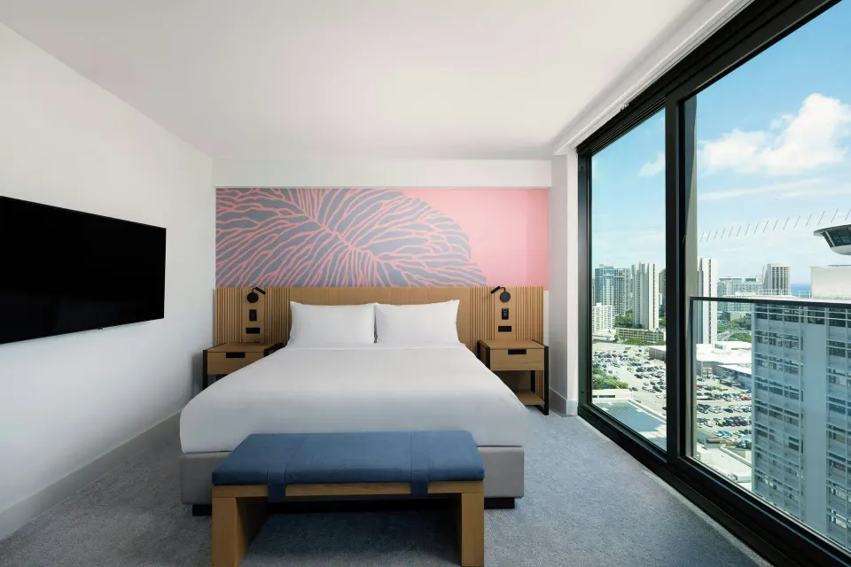 Ocean View Room king bed beside floor-to-ceiling city and ocean windows at Renaissance Honolulu Hotel & Spa.